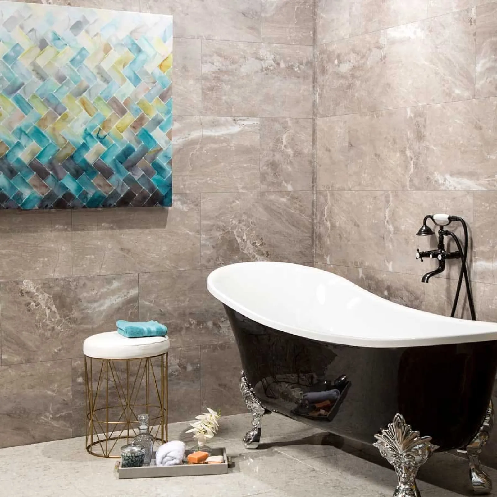 Elegant black clawfoot bathtub with vintage faucet in modern beige tiled bathroom with abstract wall art and stool.