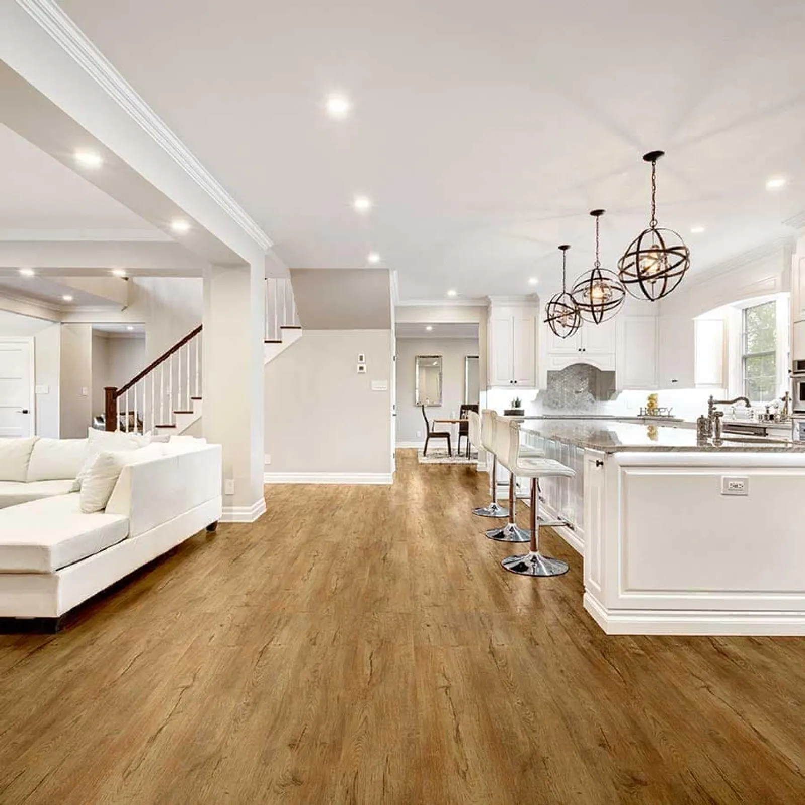 Open concept kitchen and living area with white cabinets, wood flooring, and modern pendant lights
