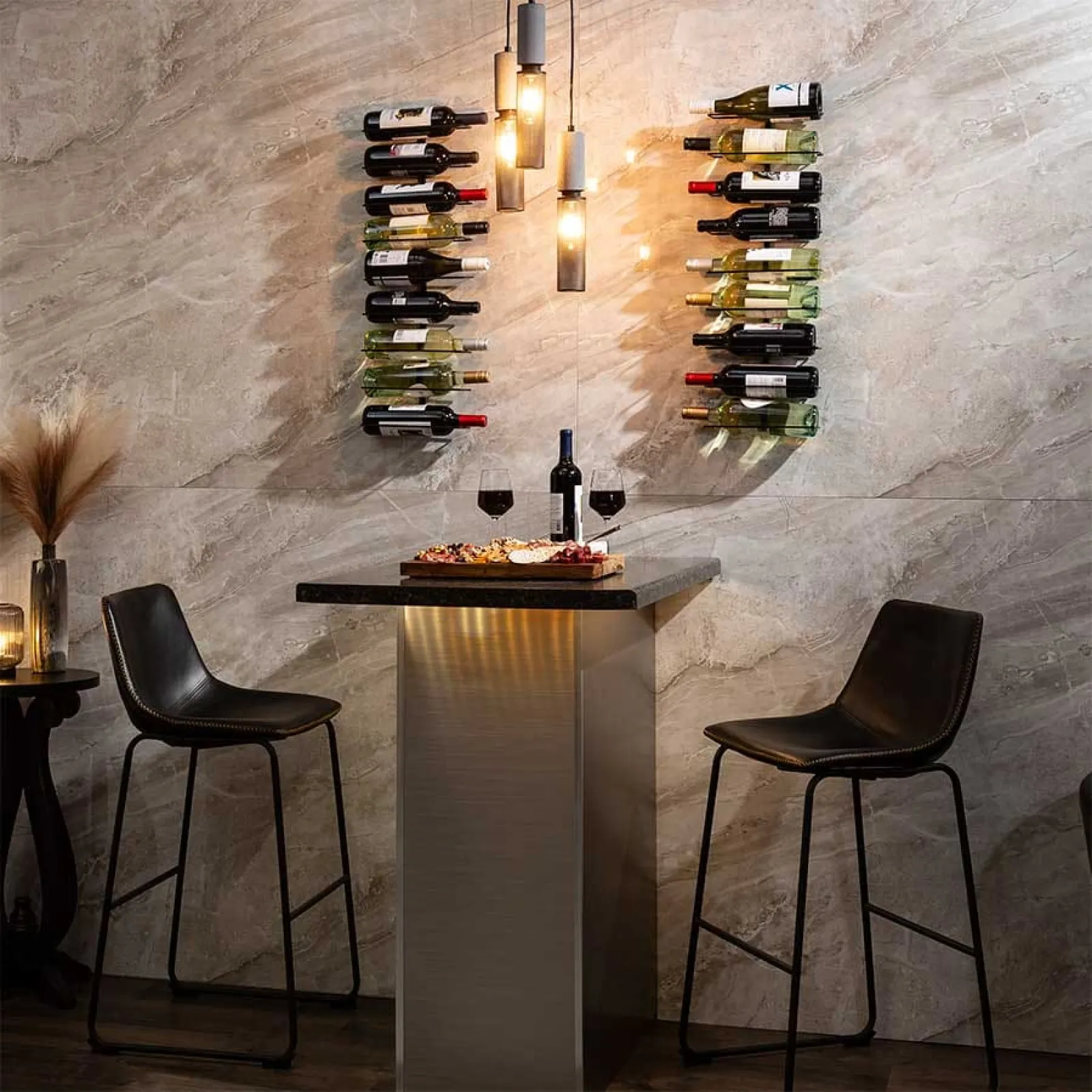 Modern wine bar setup with two black bar stools, wine bottles on wall racks, and a table with wine and snacks.