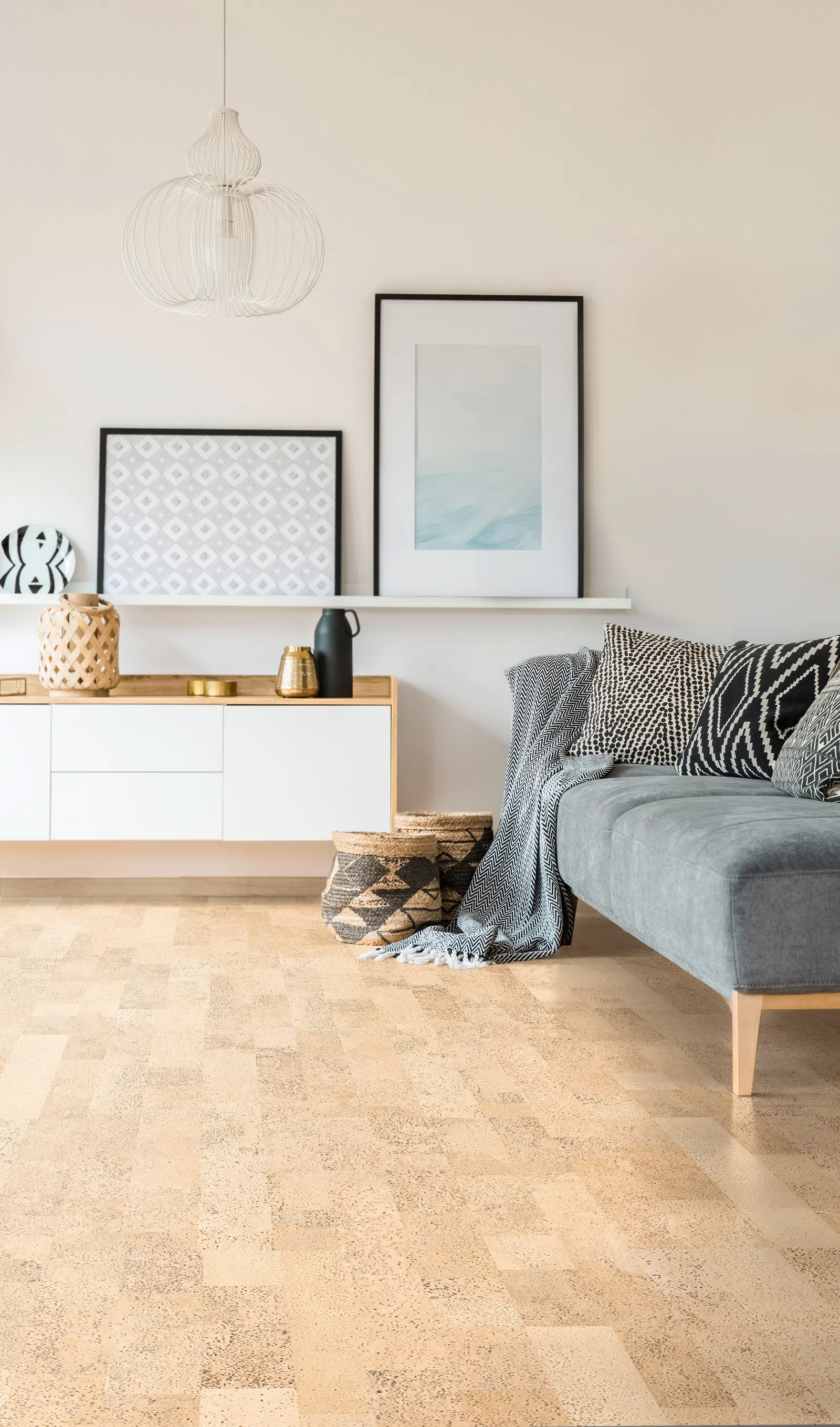 Modern living room with gray sofa, patterned cushions, wicker baskets, wooden cabinet, and minimalist wall art.