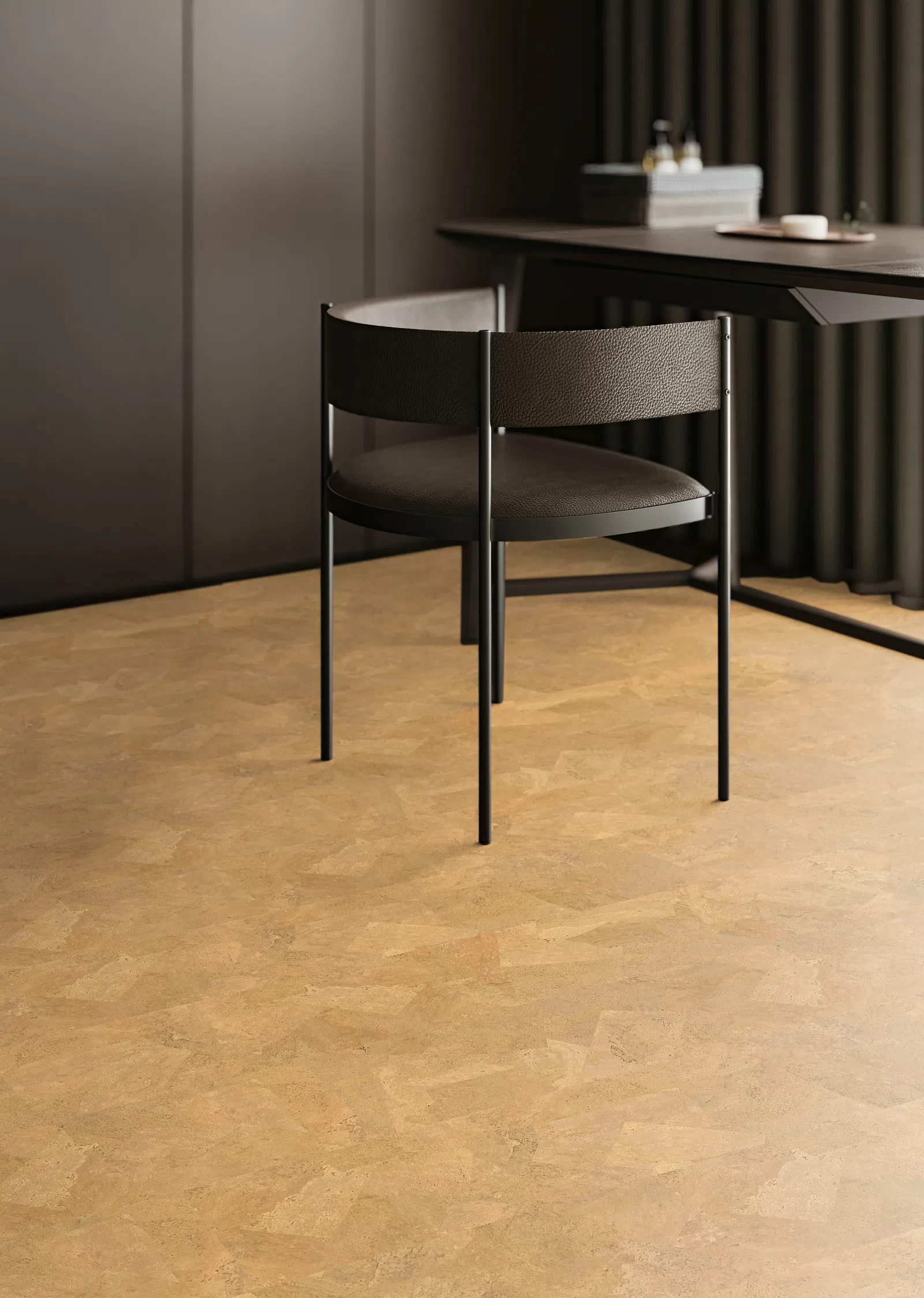 Modern black chair with textured leather and metal legs in a minimalist room with tan cork flooring.