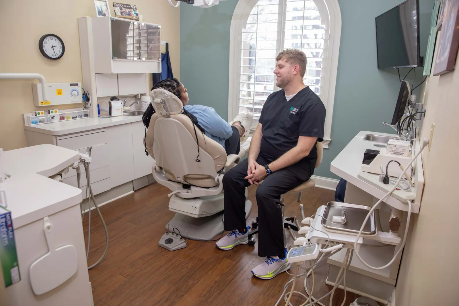 Dentist consulting a patient in a modern dental office with a dental chair and equipment.