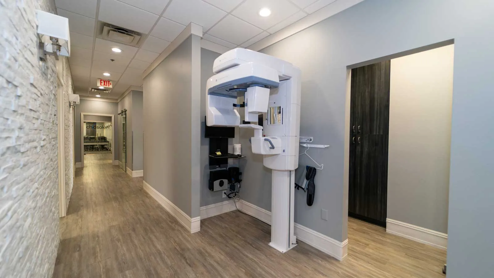 Modern dental office hallway with panoramic X-ray machine and wood flooring in neutral tones