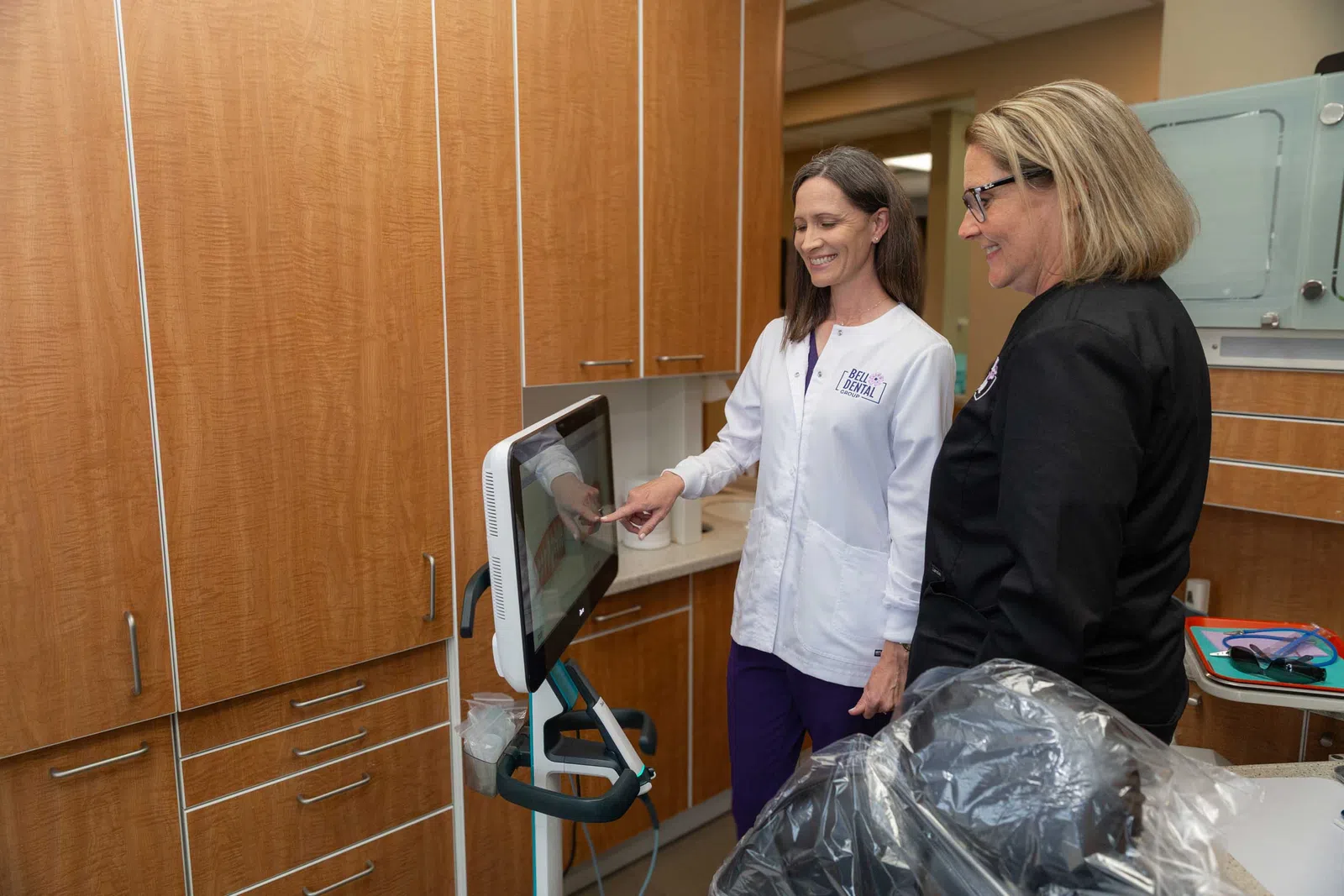 Female dentist in white coat showing patient dental imaging on a screen in a modern dental office