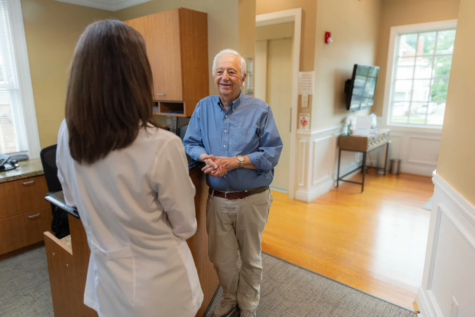 Senior man in blue shirt talking with female doctor in white coat in a medical office