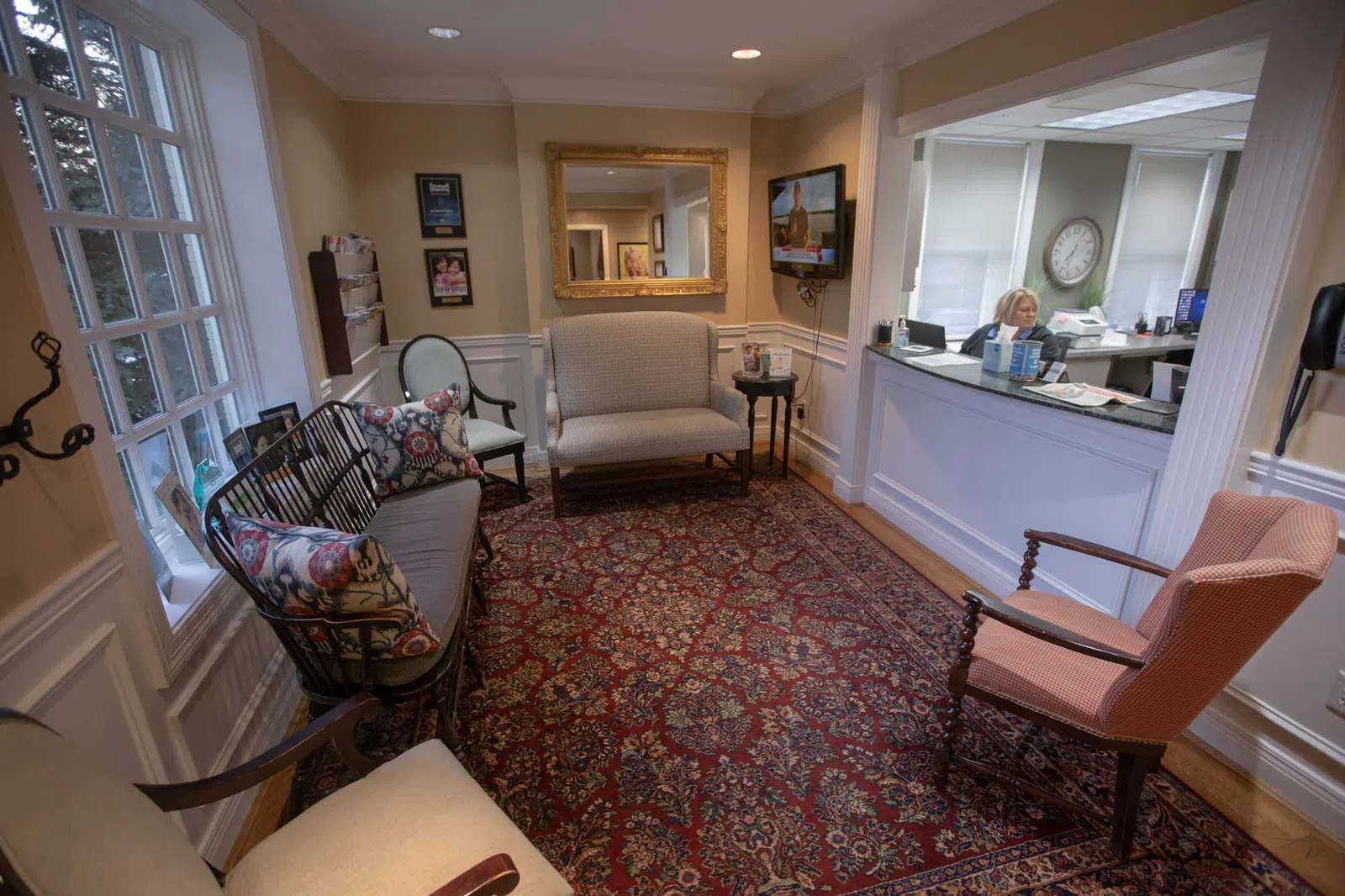 Cozy waiting room with cushioned chairs, patterned rug, a reception desk, and warm lighting in a professional setting