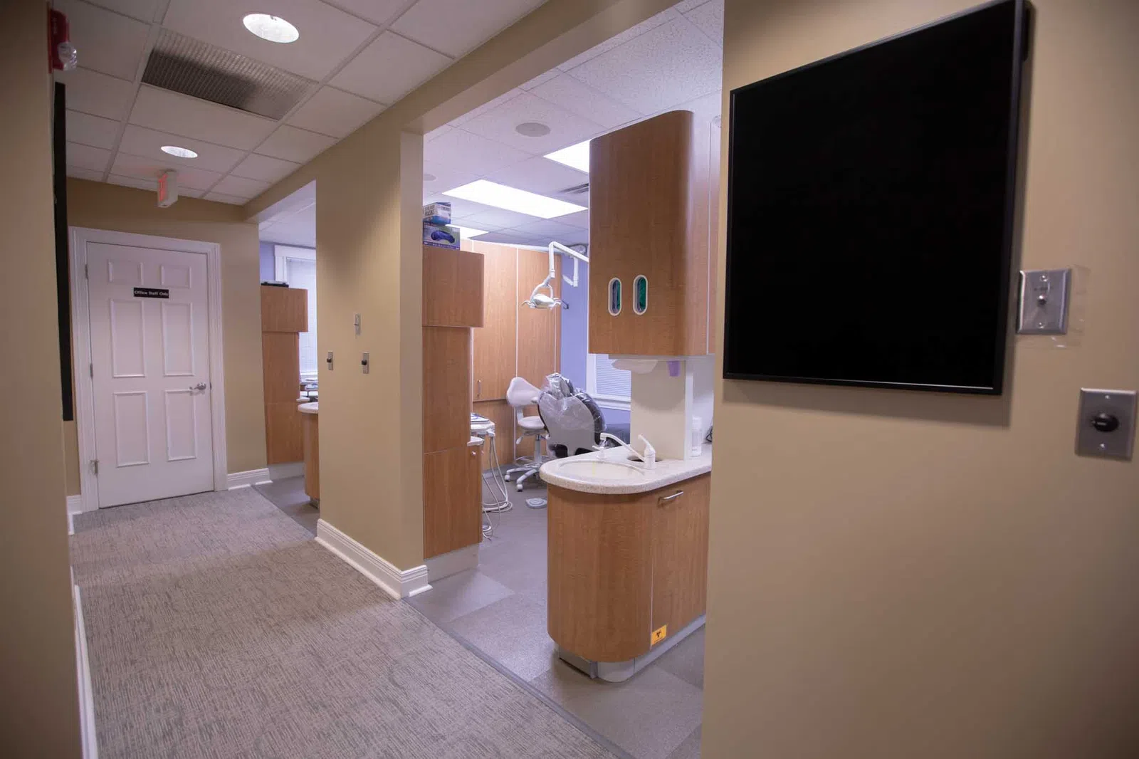 Modern dental clinic interior with beige walls, dental chair, and cabinetry in a clean, organized space
