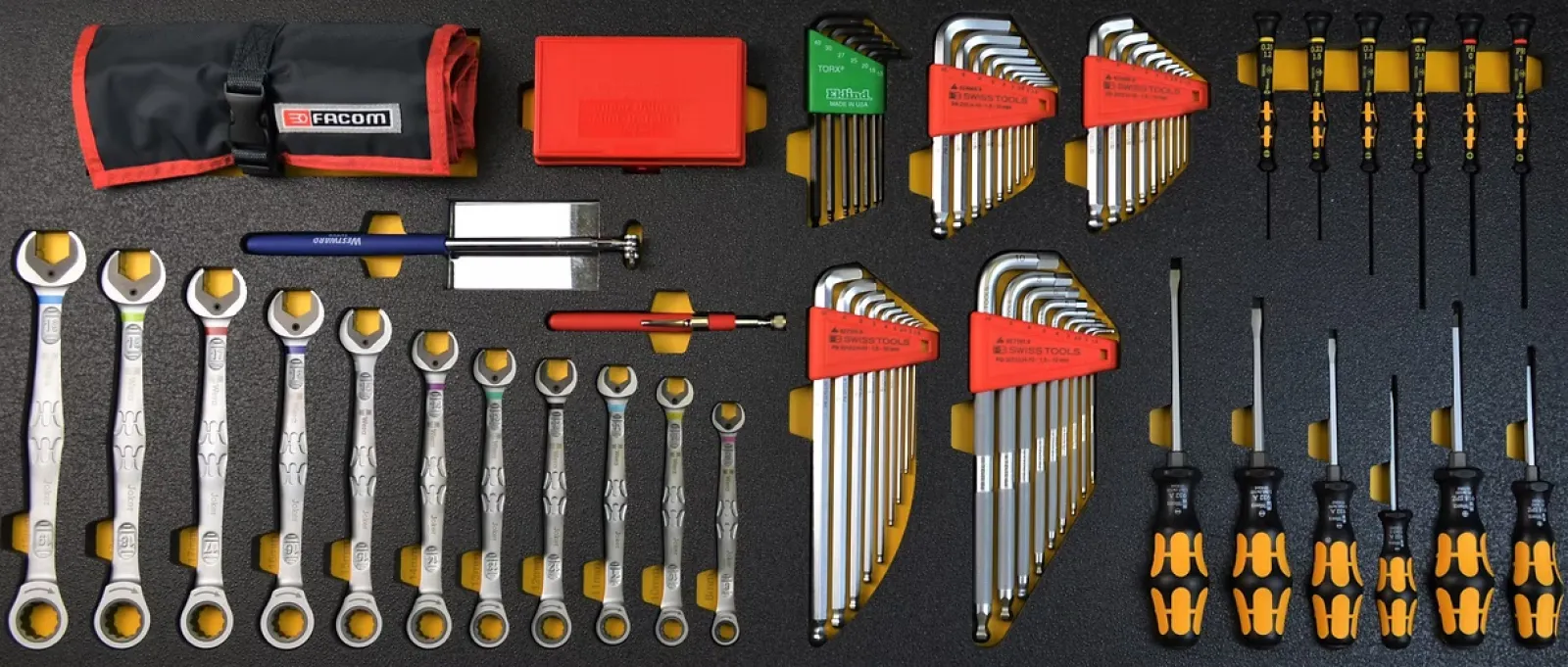 Organized set of wrenches, hex keys, and screwdrivers with black and orange handles on foam board.