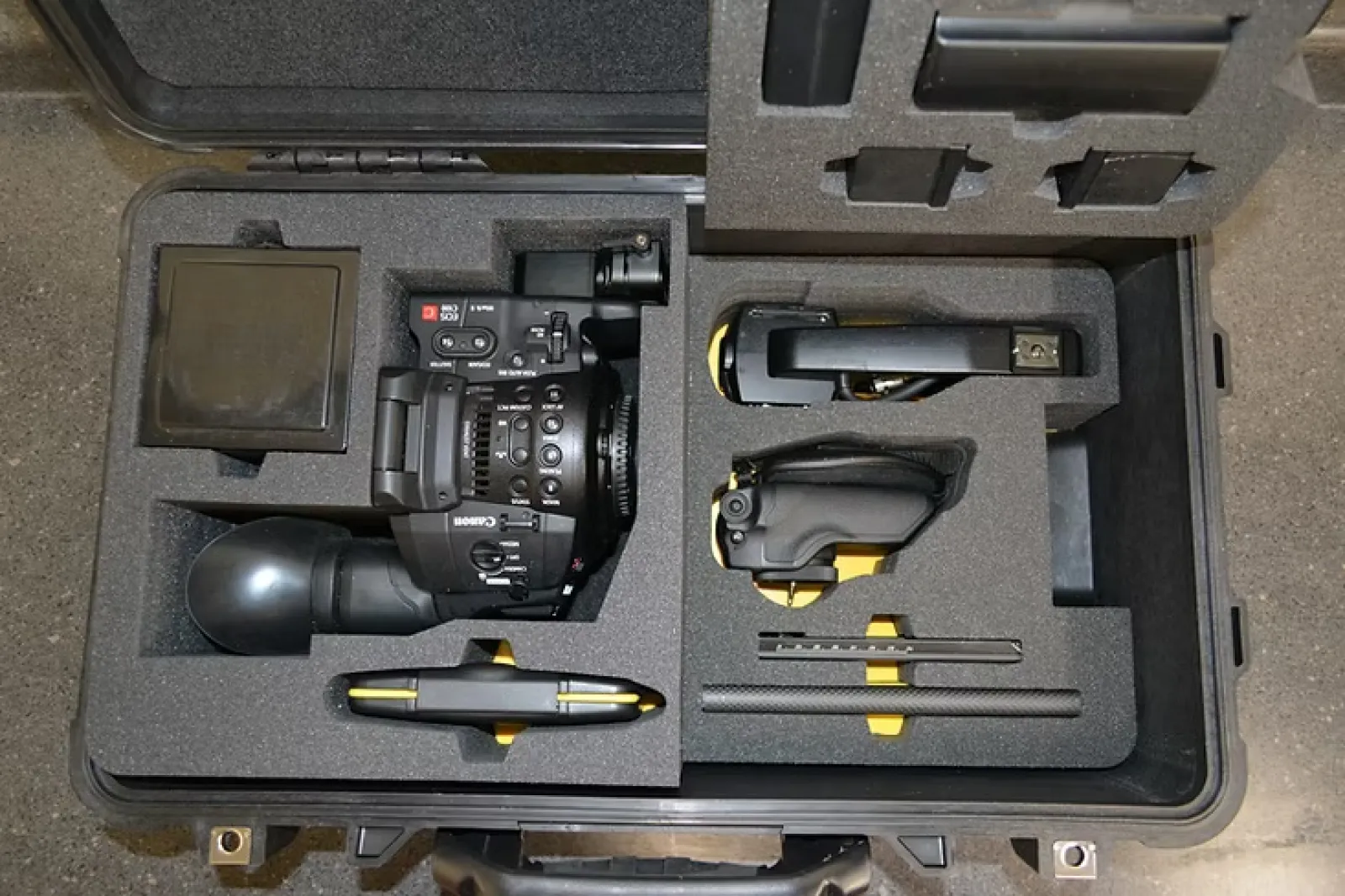 Hard case with foam inserts holding a Canon video camera and accessories for secure transport and protection.