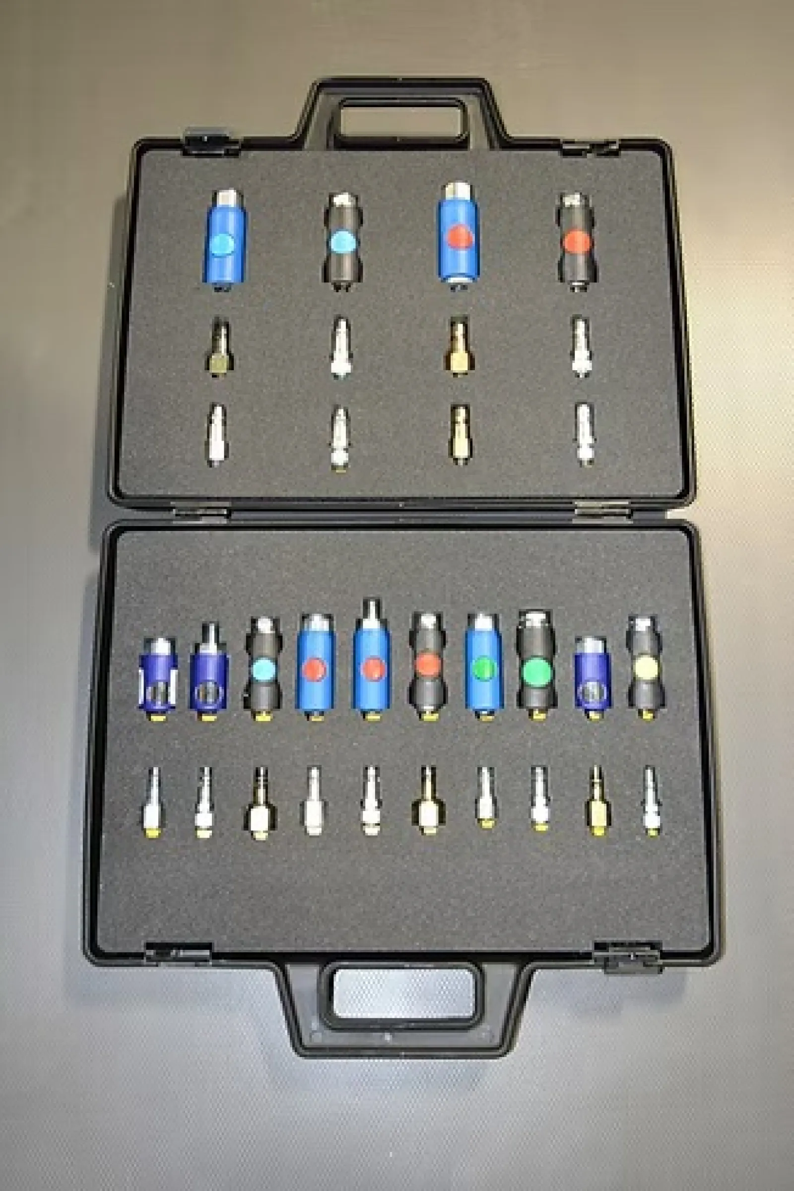 Open black carrying case with organized rows of blue and black connectors and small metal adapters.