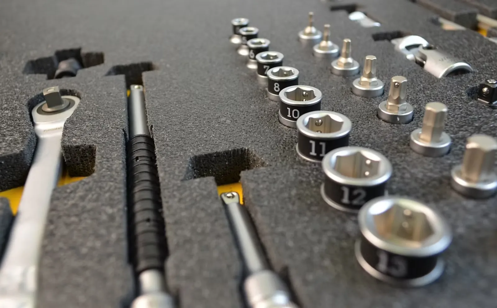 Close-up of a socket wrench set organized in a black foam case with various sizes of sockets and tools.