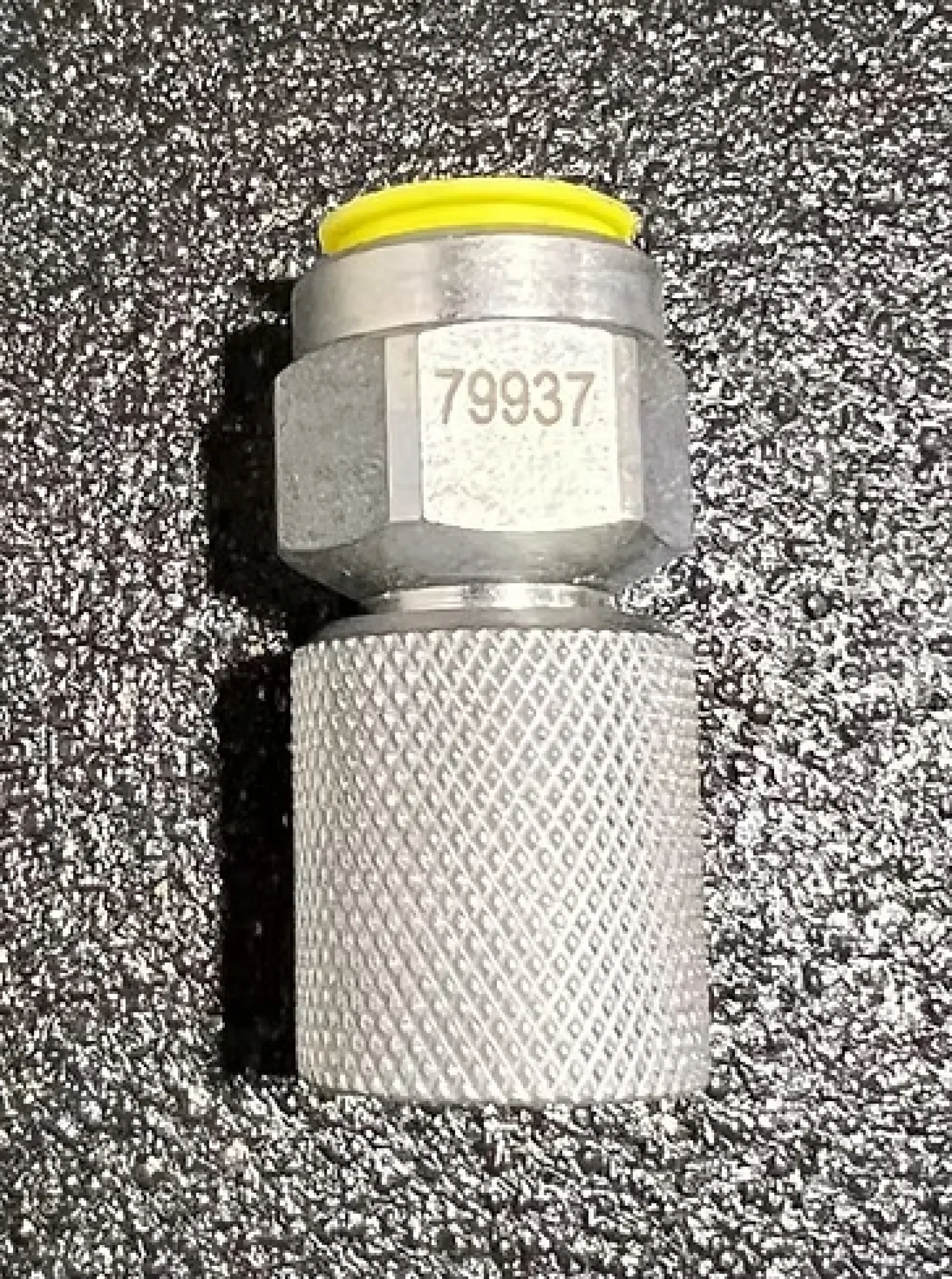 Metallic valve connector with yellow cap and textured grip marked with number 79937 on black textured surface