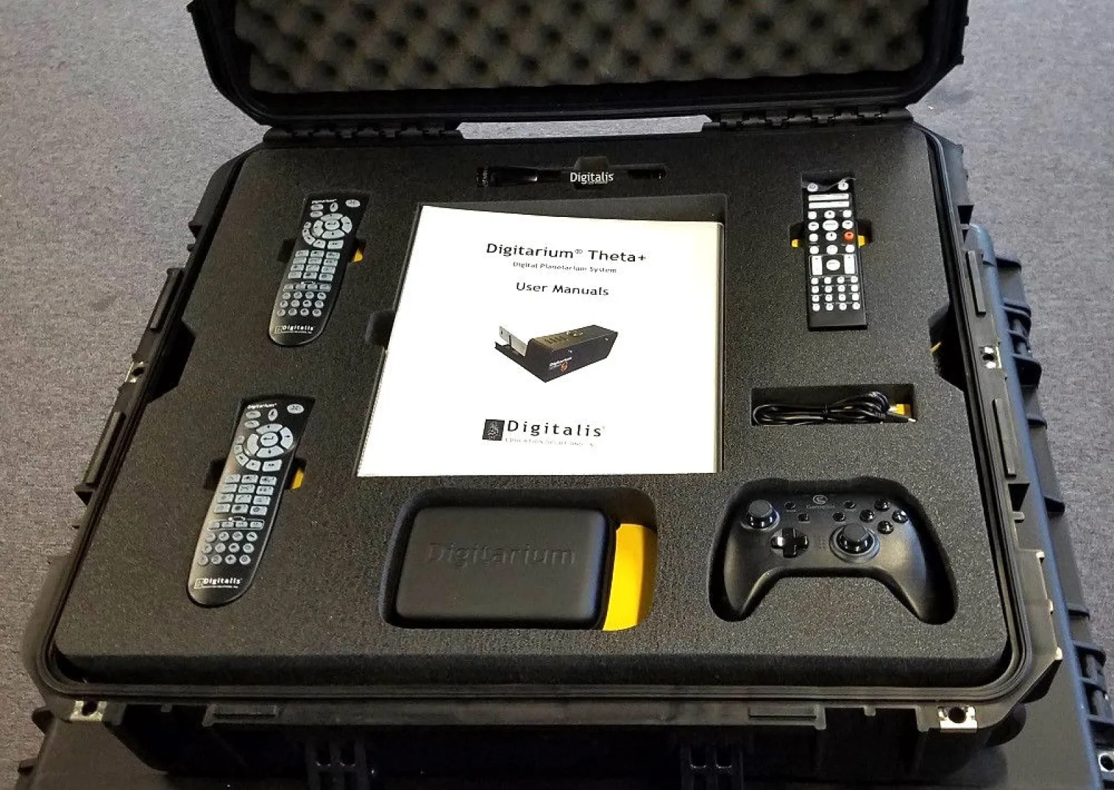 Portable Digitalis Digitarum Theta+ system with remotes, user manual, controller, and accessories organized in protective case.