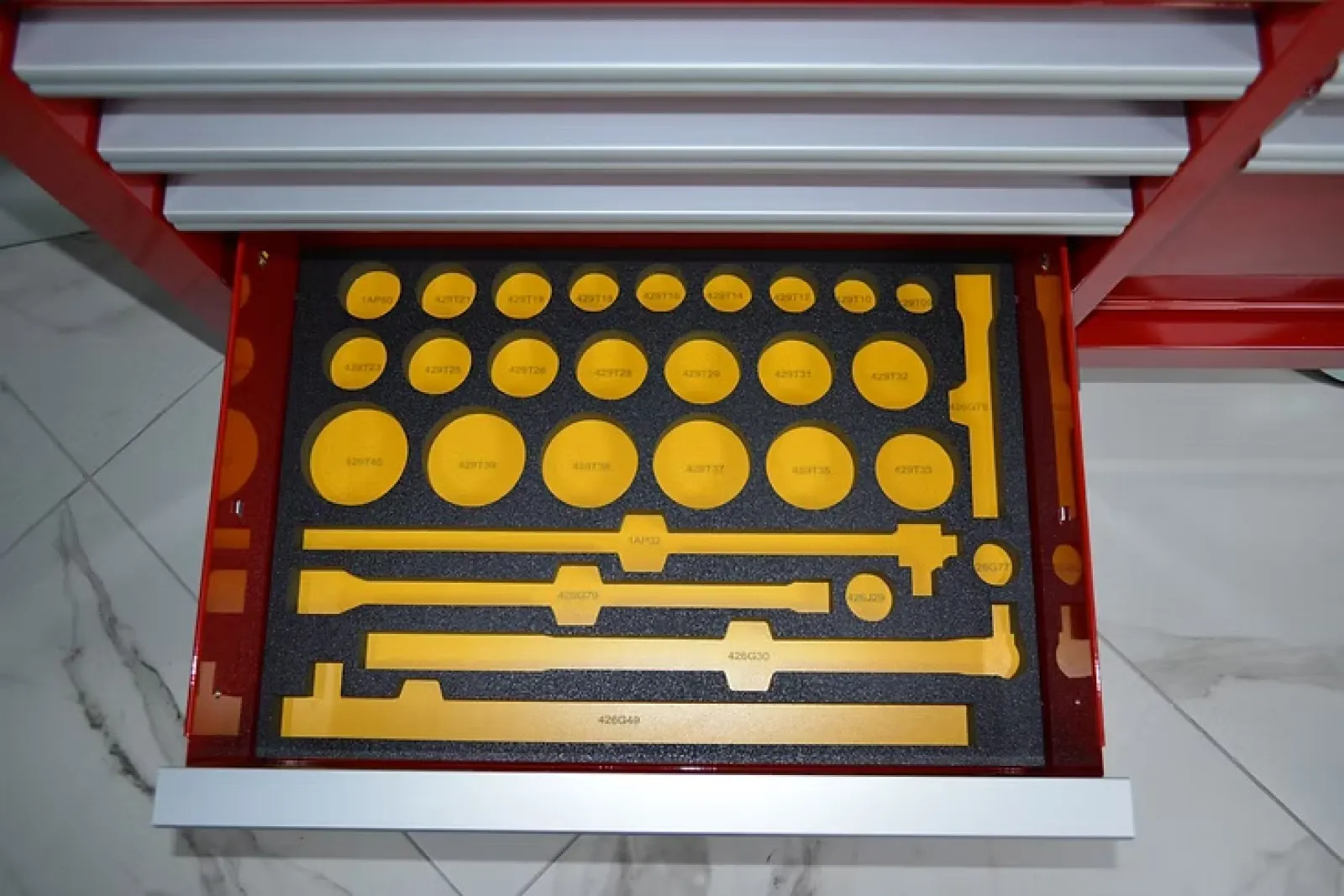 Open drawer with yellow plastic profile gauges organized in black foam for measurement and inspection tasks.