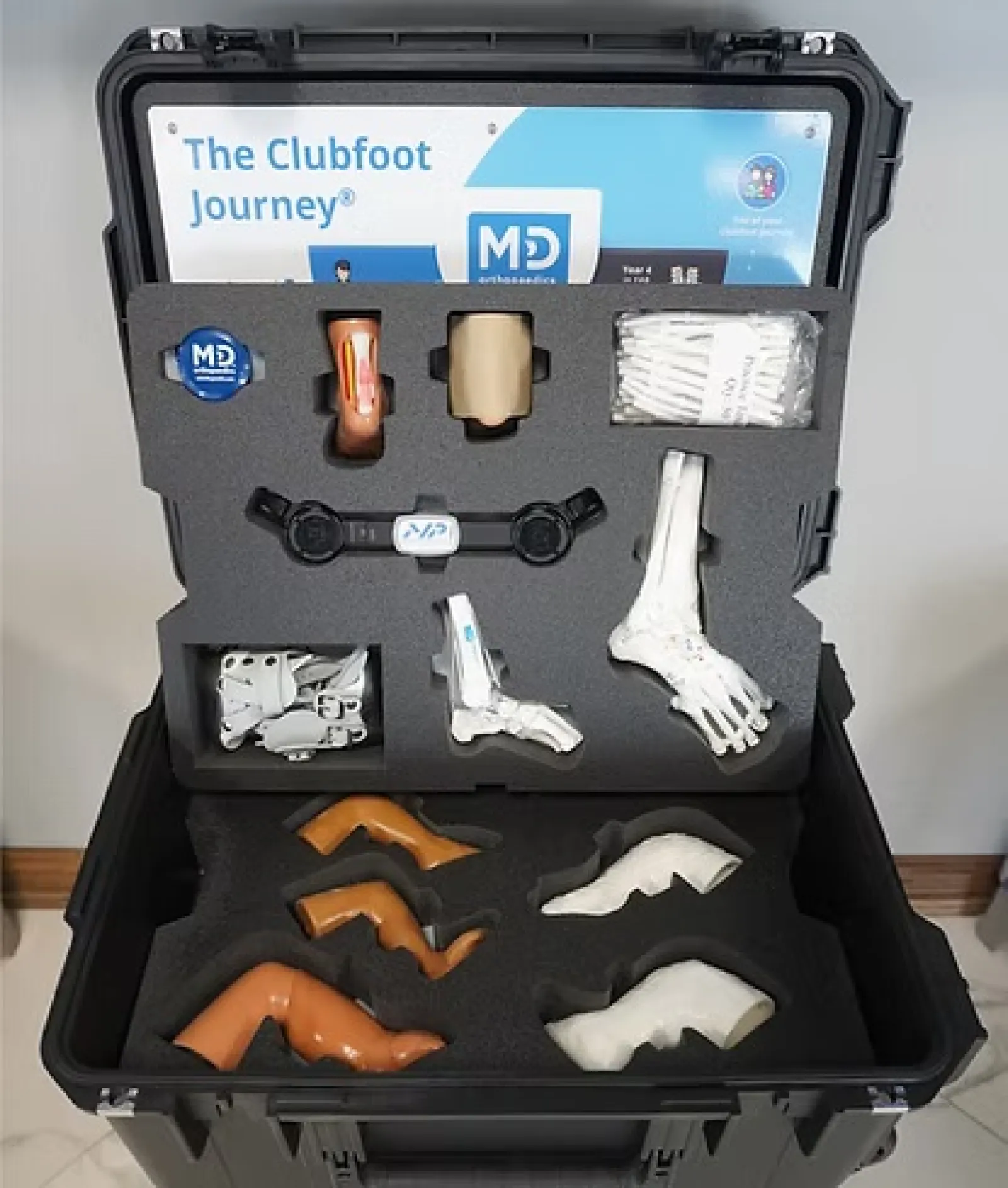 Medical training kit for clubfoot treatment with foot models, braces, and anatomical parts in a black carrying case.