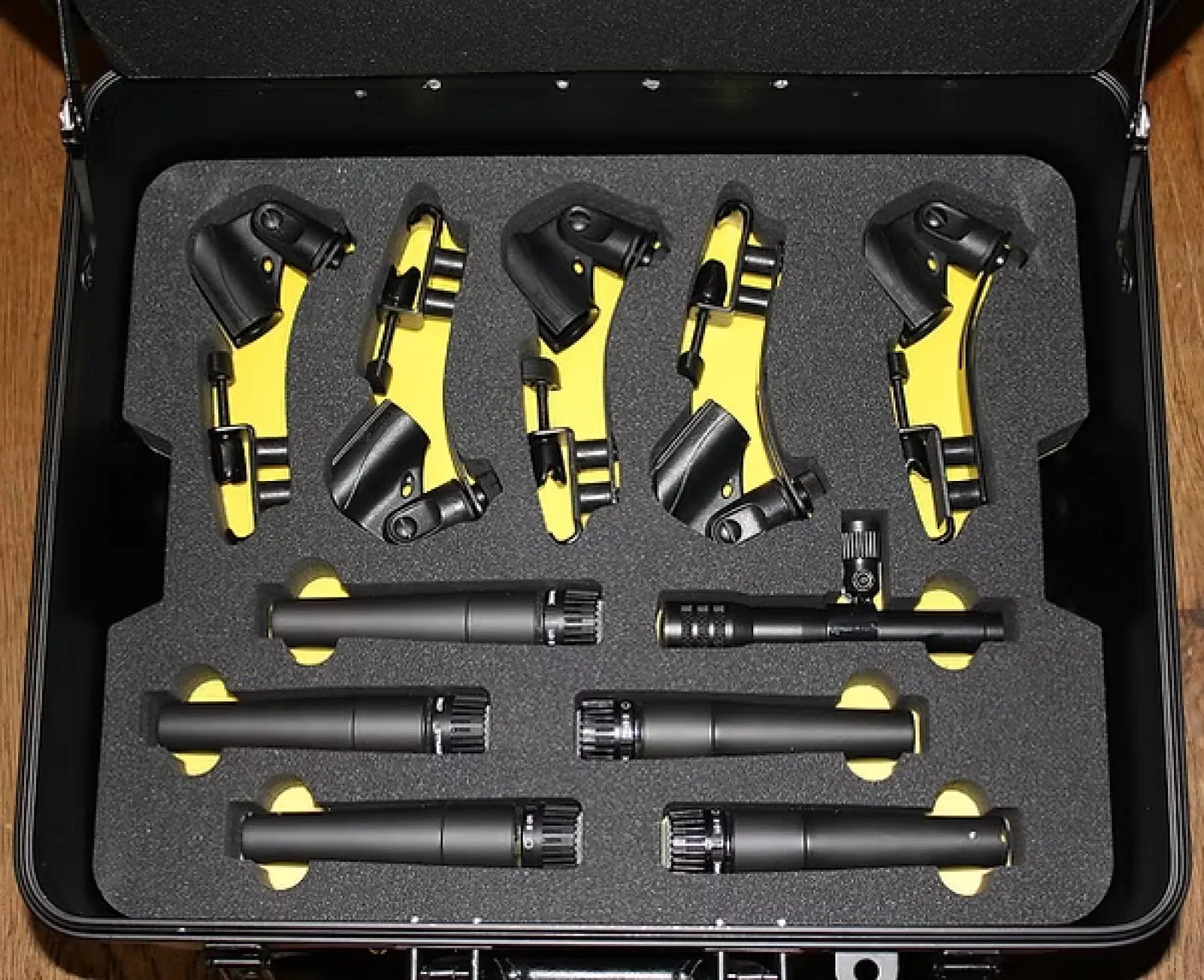 Black and yellow drum microphone clamps and eight black drum microphones in a protective foam case.