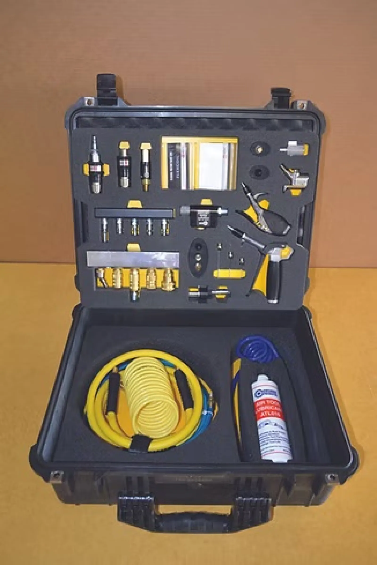 Open black toolbox with yellow coiled hose and various pneumatic tools and accessories on foam insert.