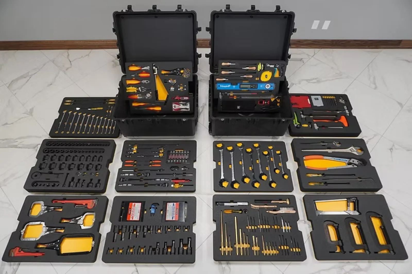 Complete professional tool kit with various hand tools neatly organized in black carrying cases on a tiled floor.