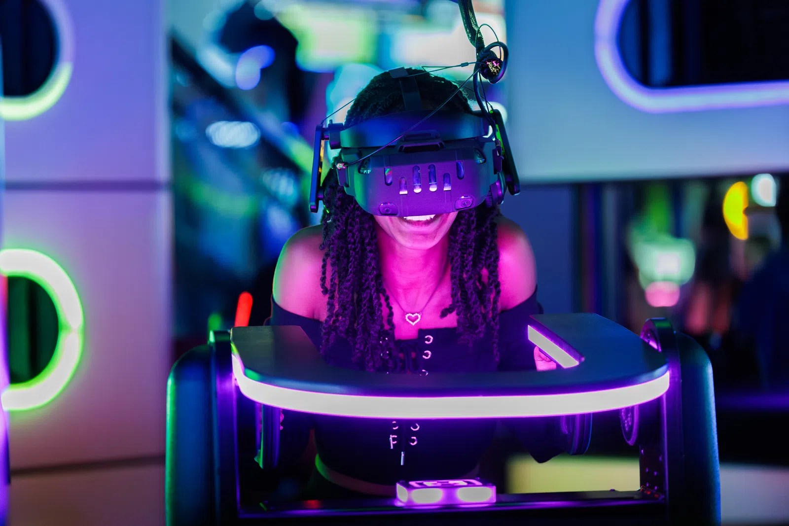 Young woman gaming with VR headset in neon-lit arcade room, smiling and immersed in virtual reality experience.