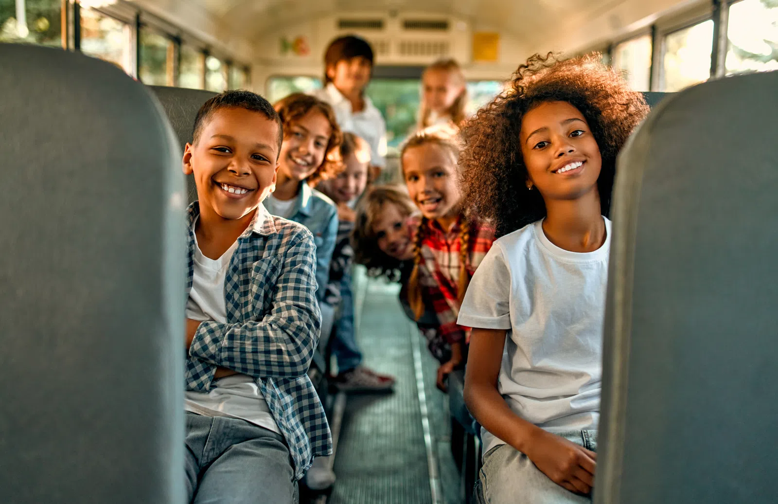 Happy diverse children smiling together on a school bus, showcasing friendship and joy.