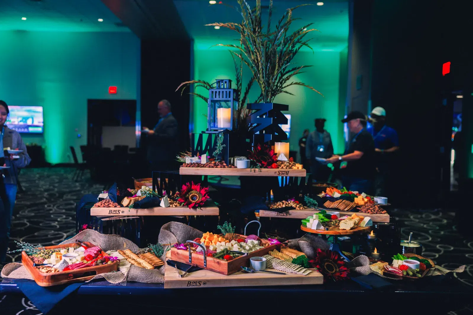 Elegant buffet table with assorted cheeses, crackers, fruits, and decorative candles in event setting.