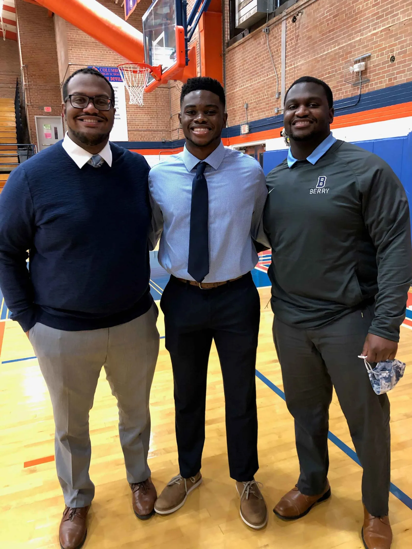 The Palmer brothers pose together in a high school gym.