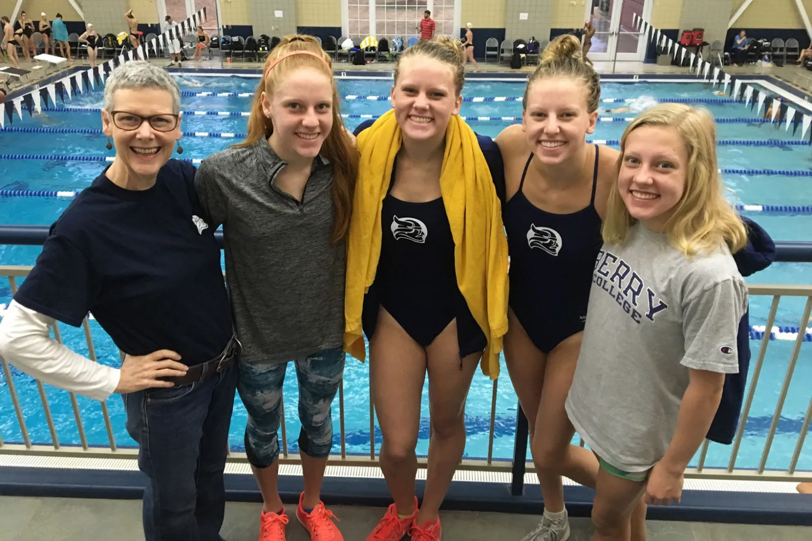 Four sisters and their mom pose in front of a swimming pool.