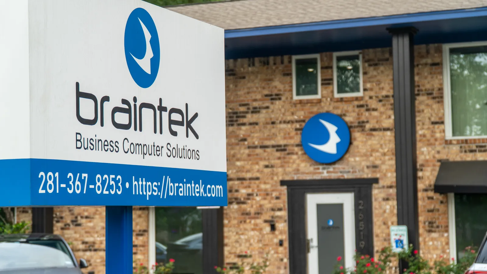 Braintec business computer solutions sign with contact info in front of brick office building