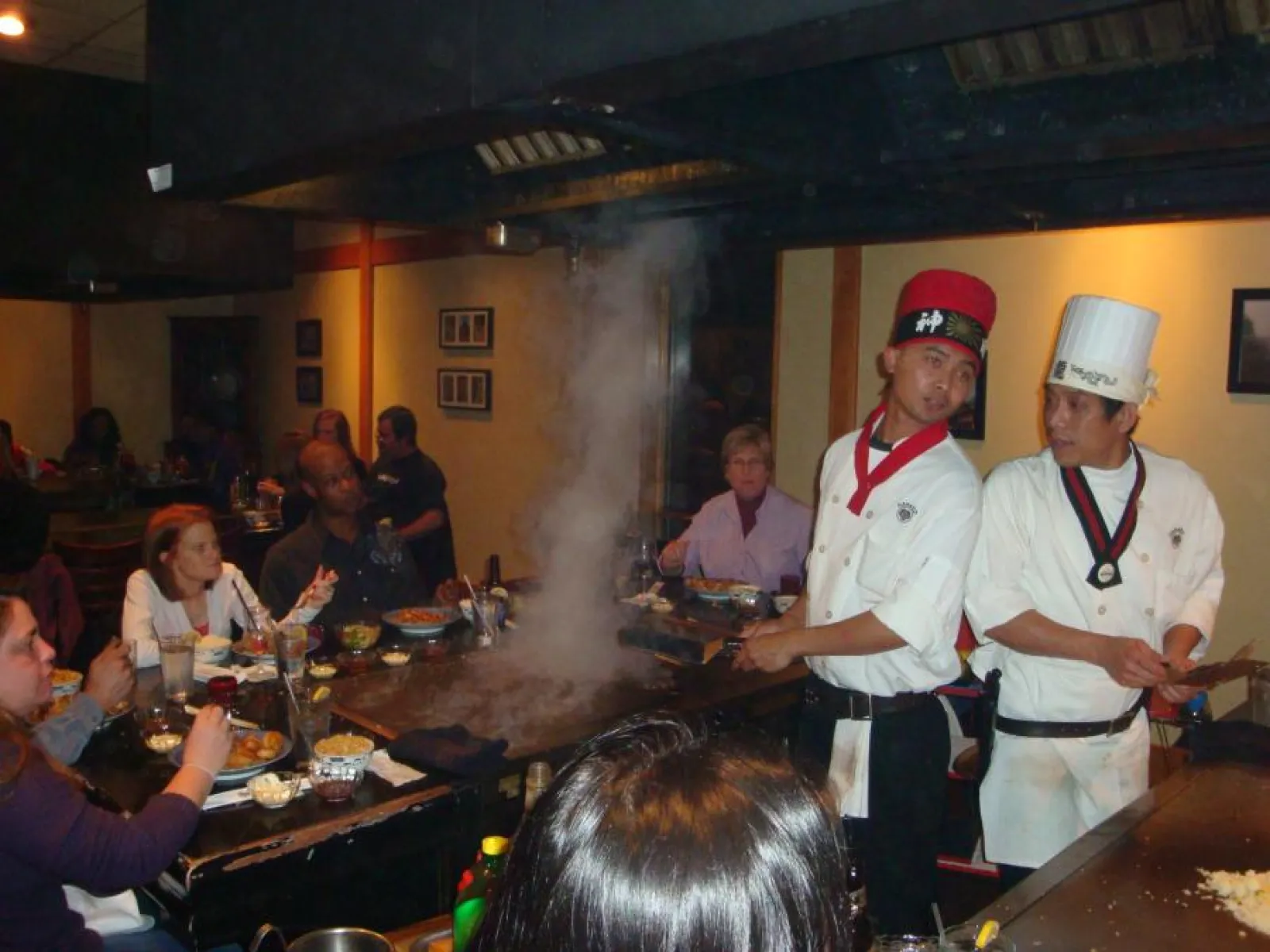 a group of people sitting at a hibachi grill