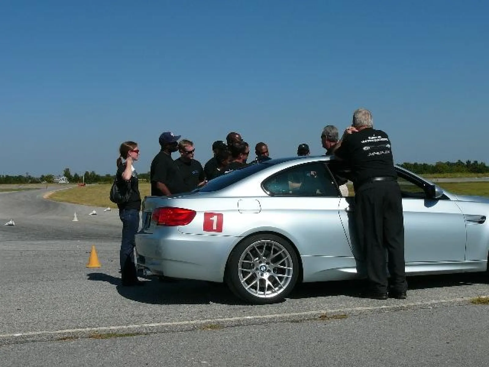 people standing around a car on a test track