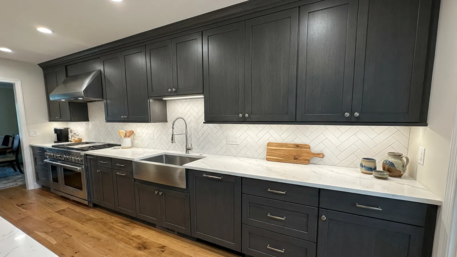 Modern kitchen with dark wood cabinets, white marble countertops, farmhouse sink, and herringbone tile backsplash.