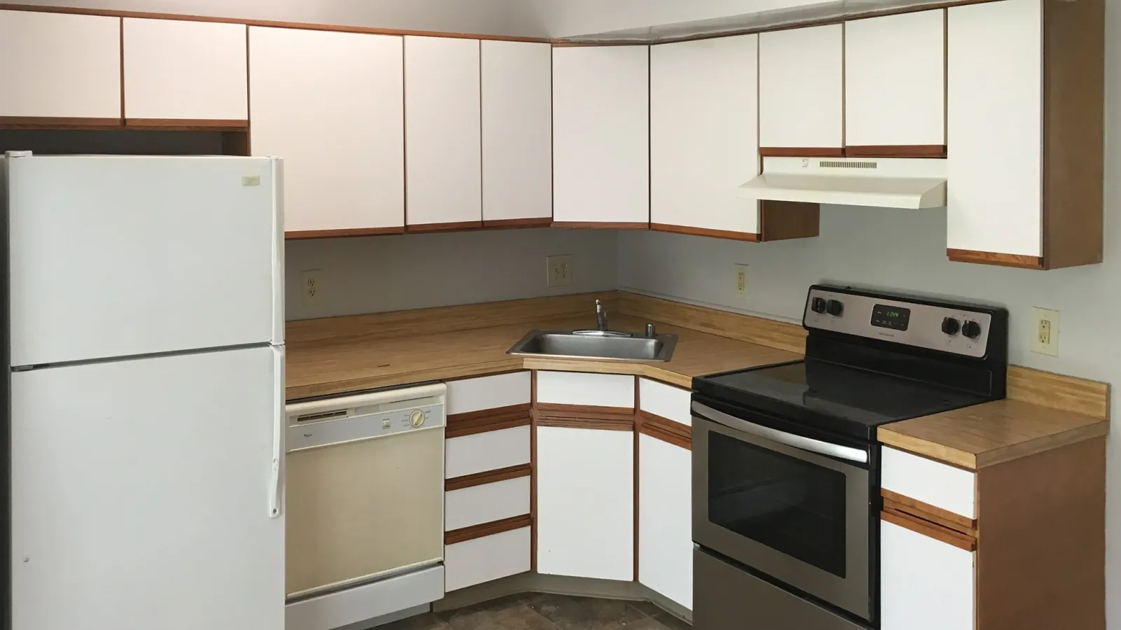 Compact kitchen with white cabinets, wood countertops, stainless steel stove, white refrigerator, and tiled floor.