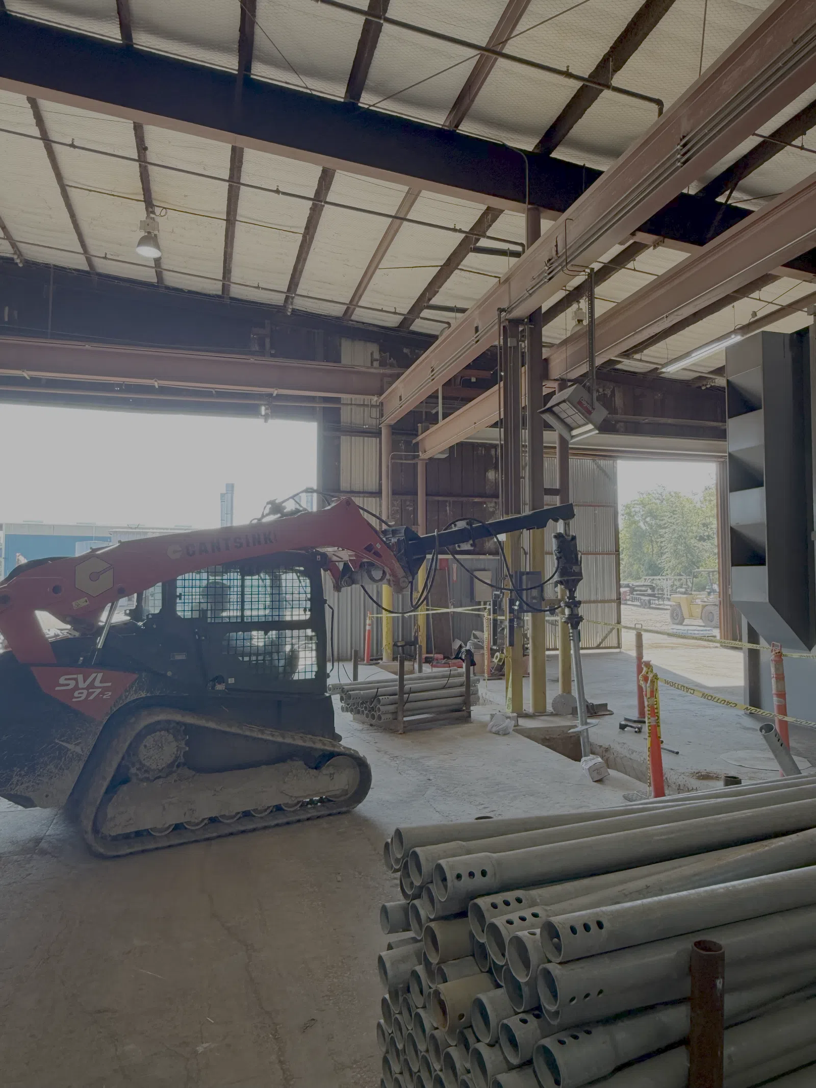 Red Cantsink SVL 97-2 skid steer loader inside warehouse installing helical piles