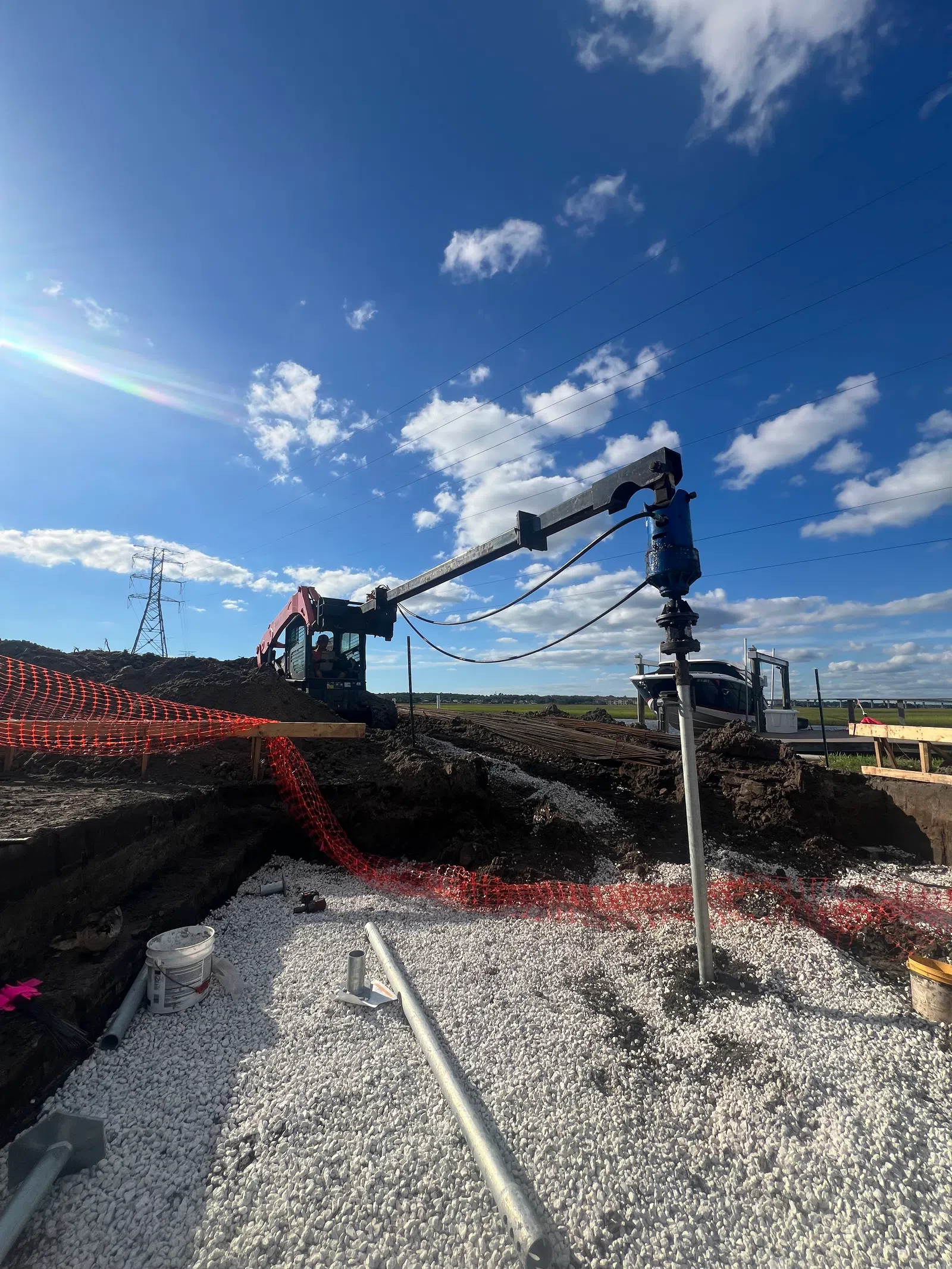 Construction site with heavy machinery drilling helical piles.