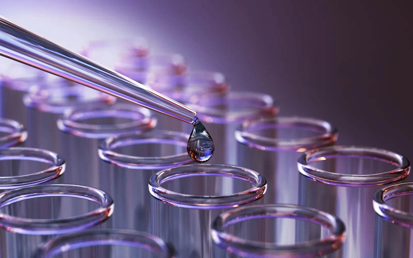 Close-up of a pipette dropping liquid into clear test tubes under purple lighting in a lab setting
