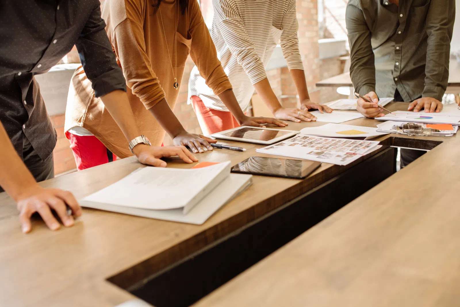 Team of diverse professionals collaborating over documents and tablets in a modern office meeting.