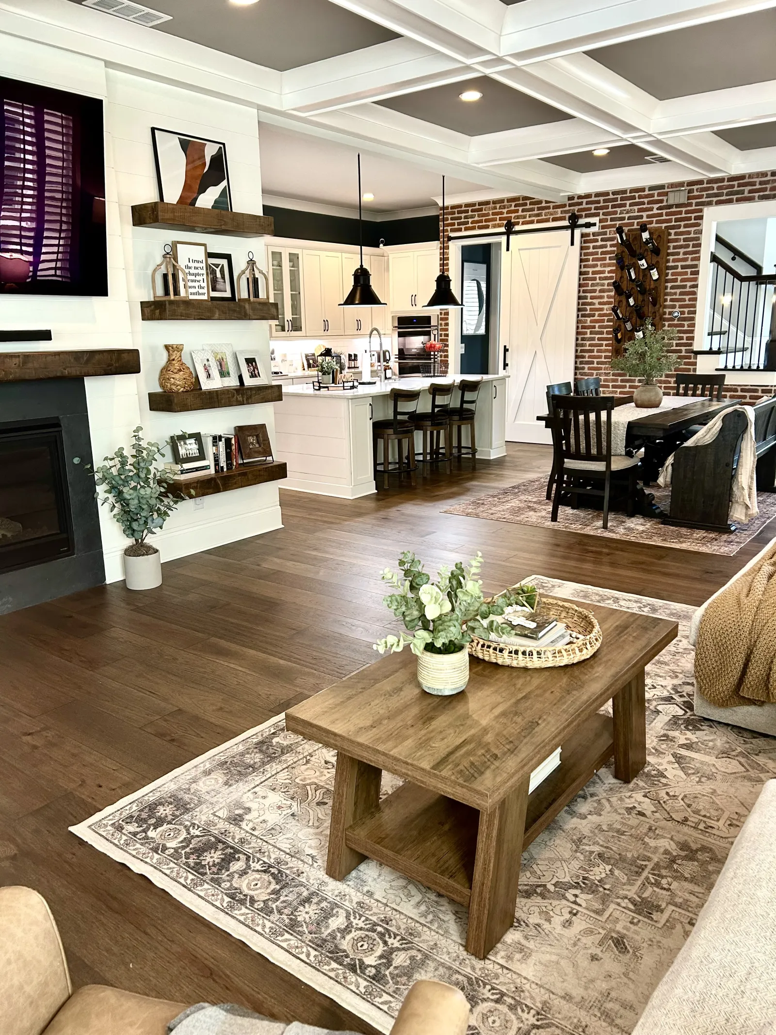 Open living space with wooden floors, modern kitchen, dining area, farmhouse decor, and cozy seating arrangement