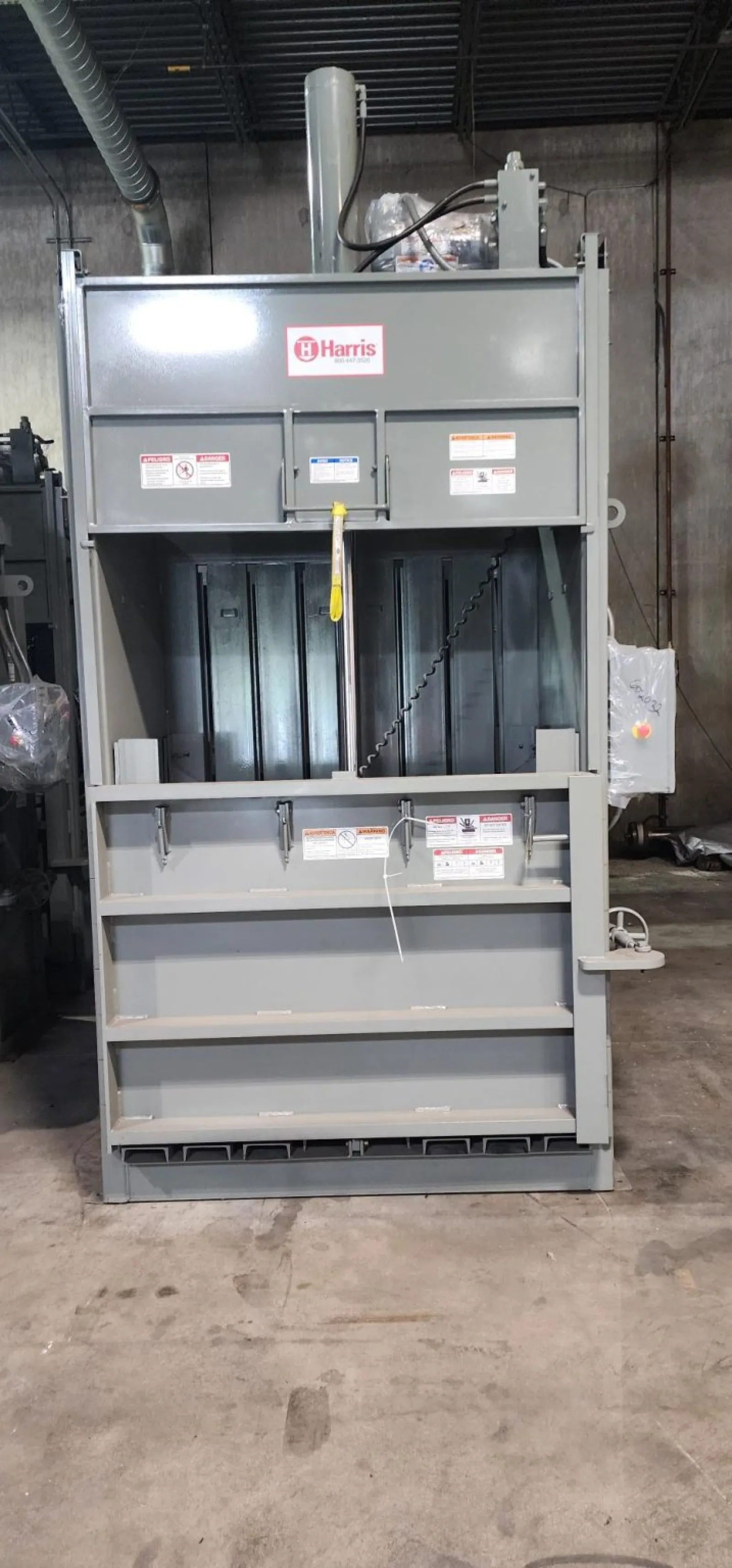 Industrial gray Harris baler machine in warehouse for compacting recyclable materials safely