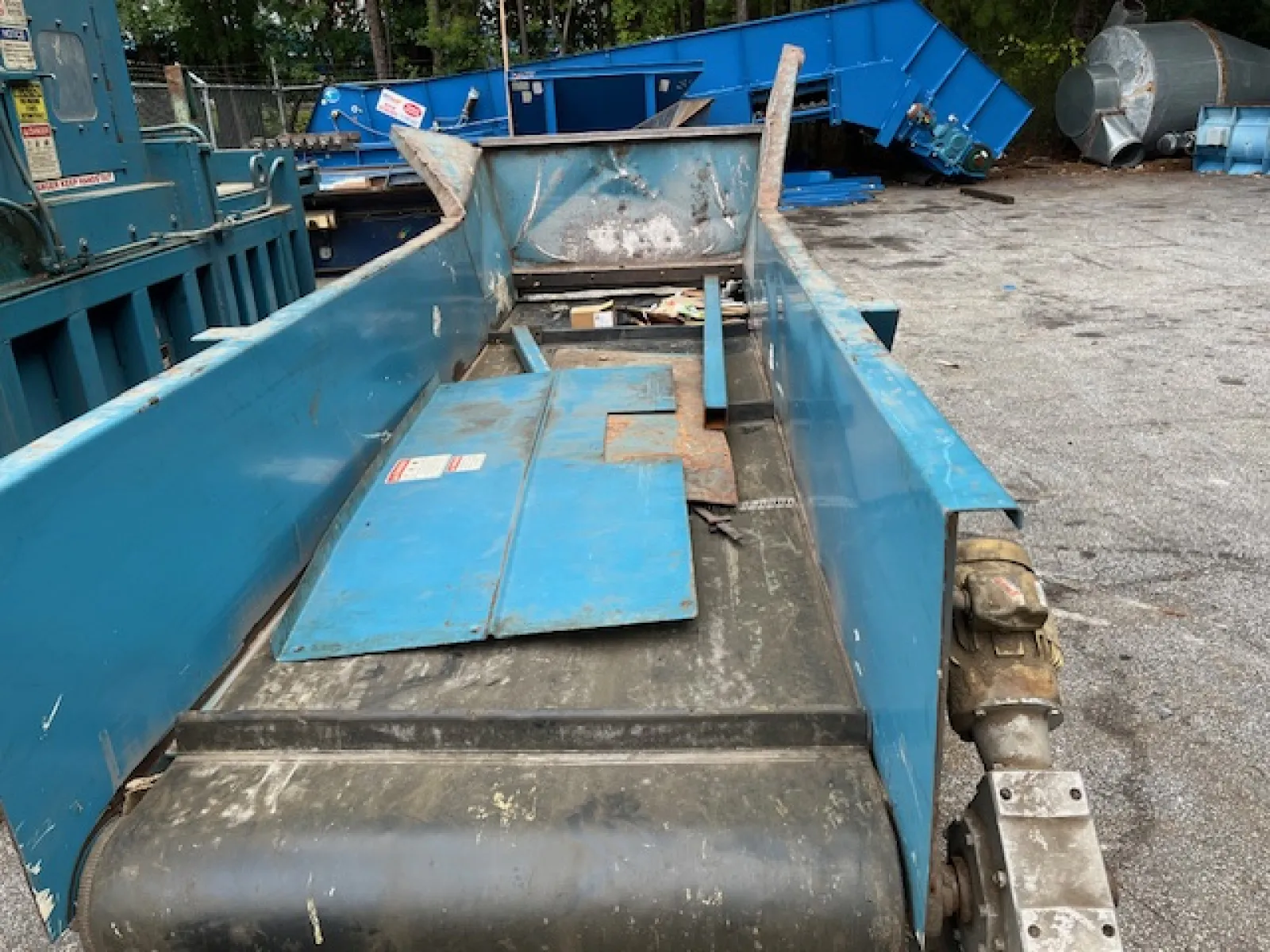 Close-up of an industrial blue conveyor belt system with metal components in an outdoor setting