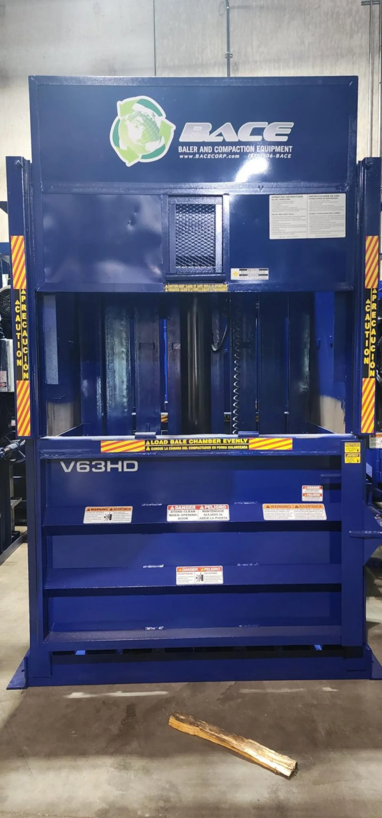Blue industrial baler machine V63HD by BACE for baling and compaction with safety warning labels