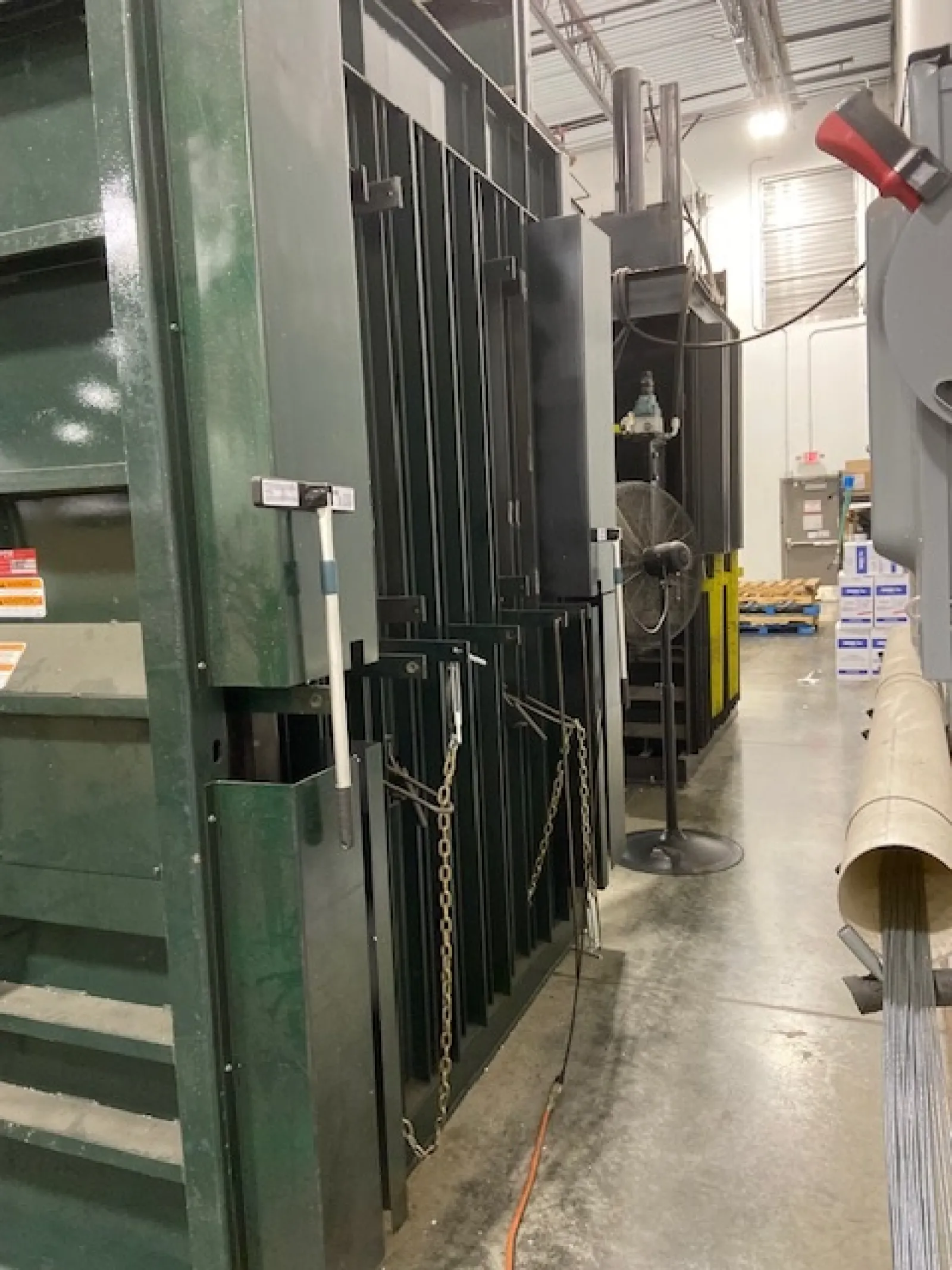 Industrial machinery and equipment lined up in a warehouse with concrete flooring and overhead lighting.