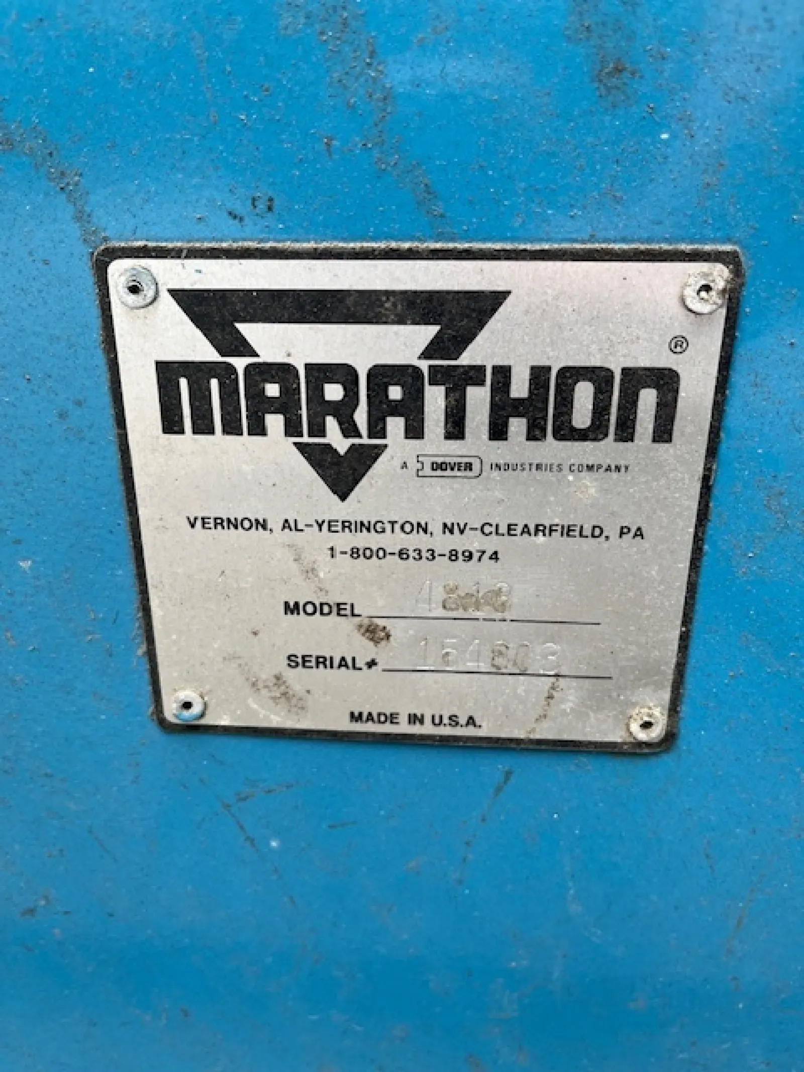 Metal identification plate with Marathon logo and manufacturing details on a blue surface.