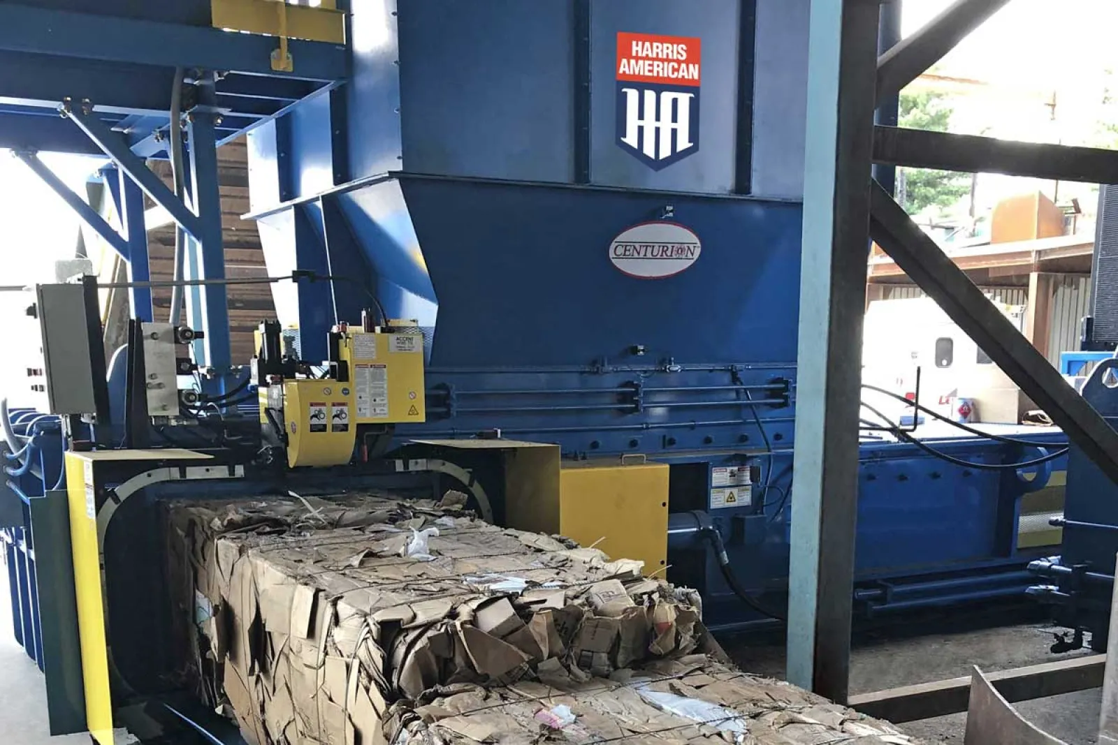 Industrial Harris American cardboard baler compressing and bundling cardboard waste in a factory