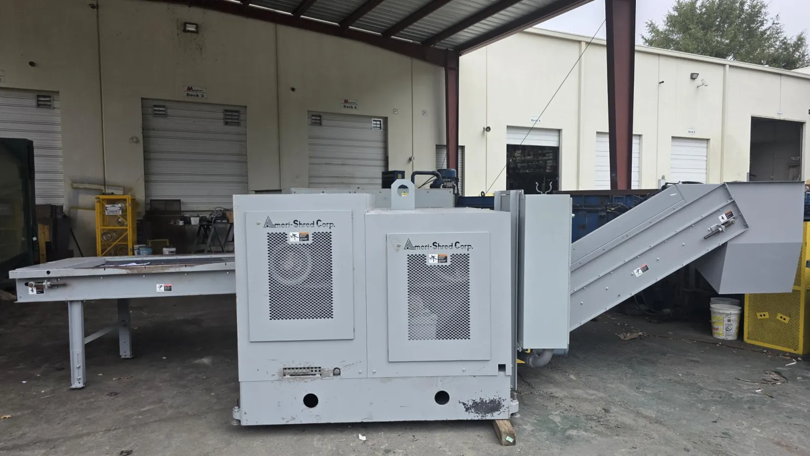 Industrial Ameri-Shred Corp machine in warehouse with conveyor belt and loading table.