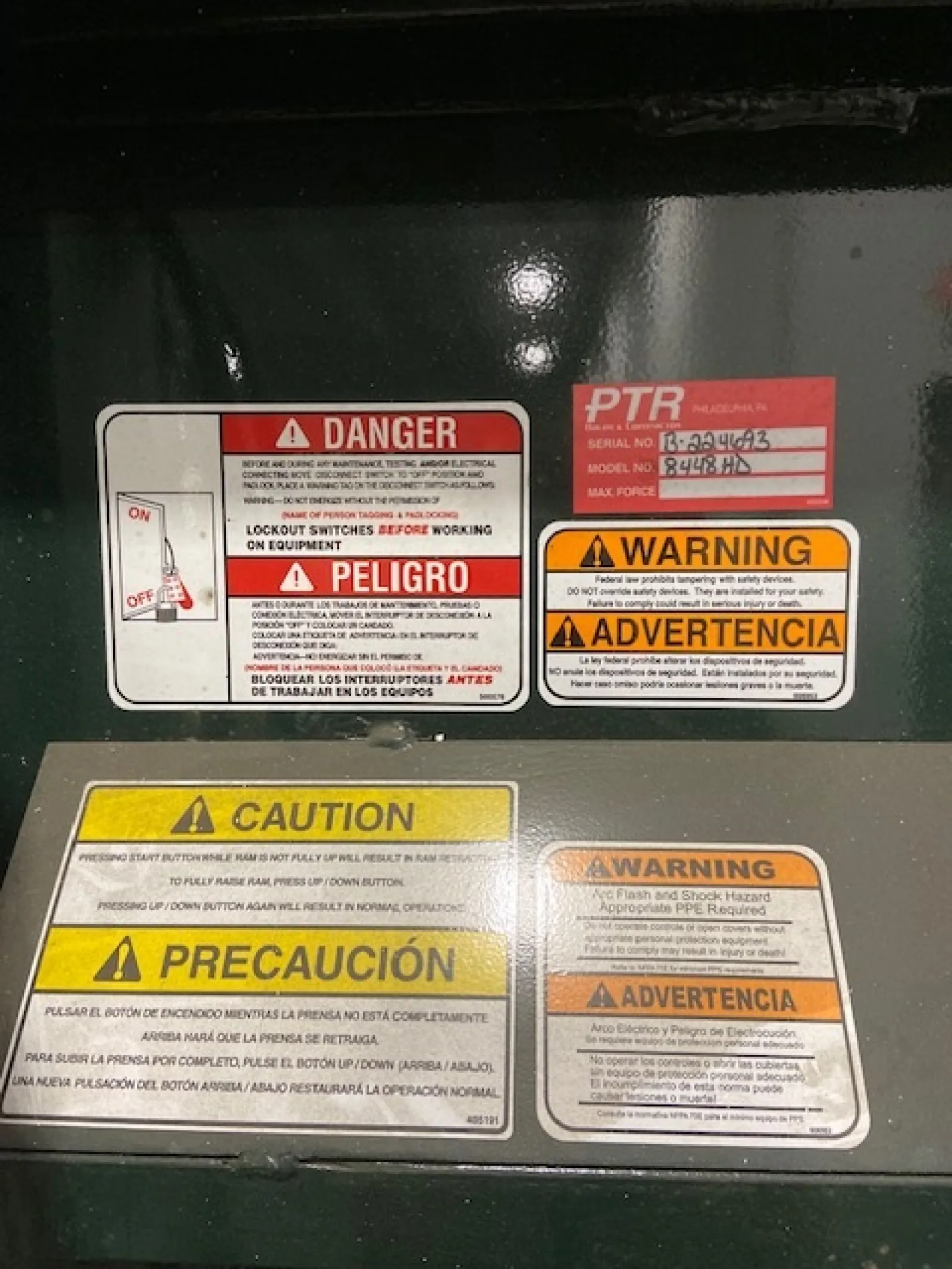 Multiple bilingual safety labels including danger, warning, and caution notices on industrial equipment panel.