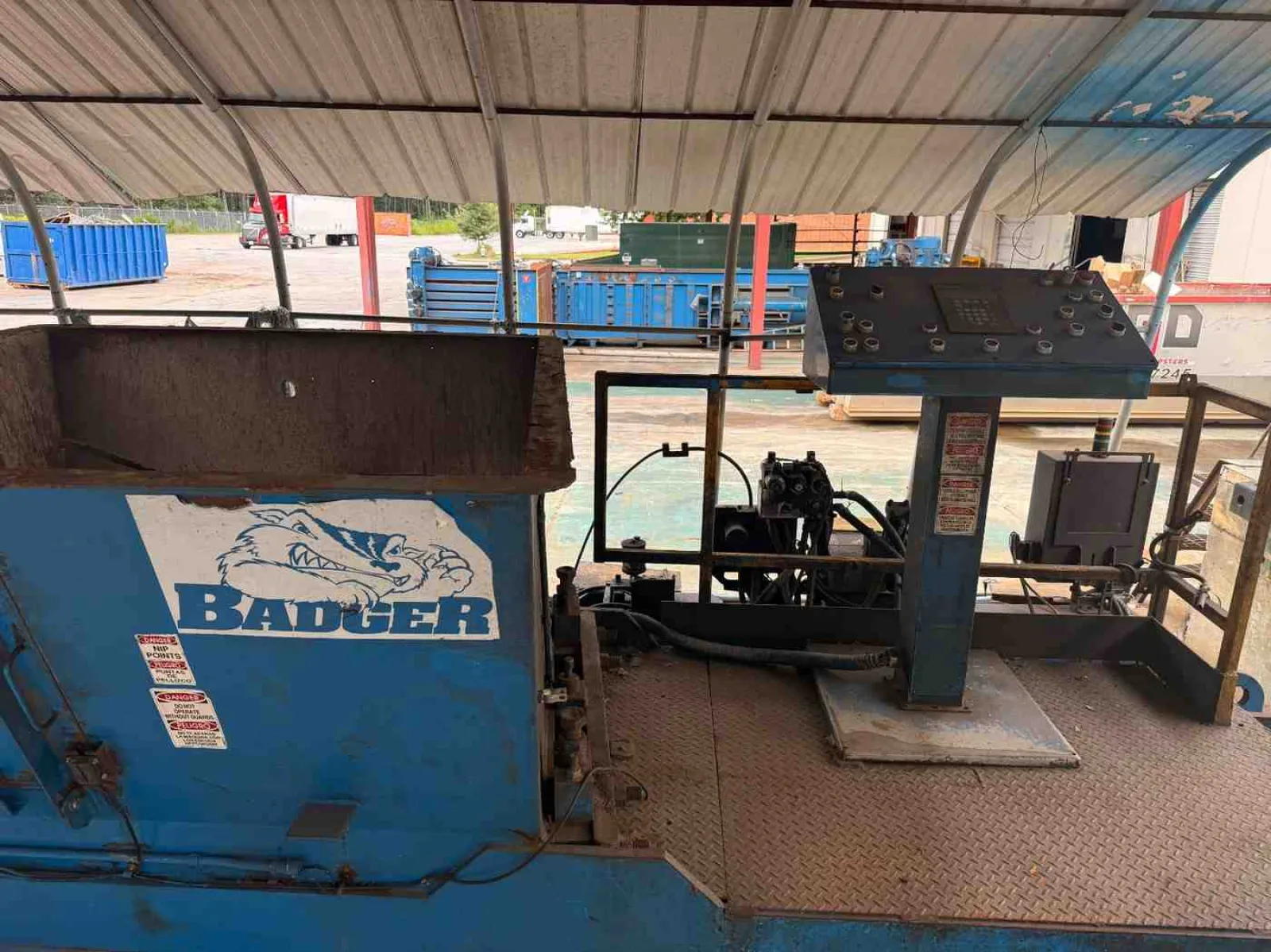 Blue industrial Badger machine with control panel under metal roof at outdoor worksite.