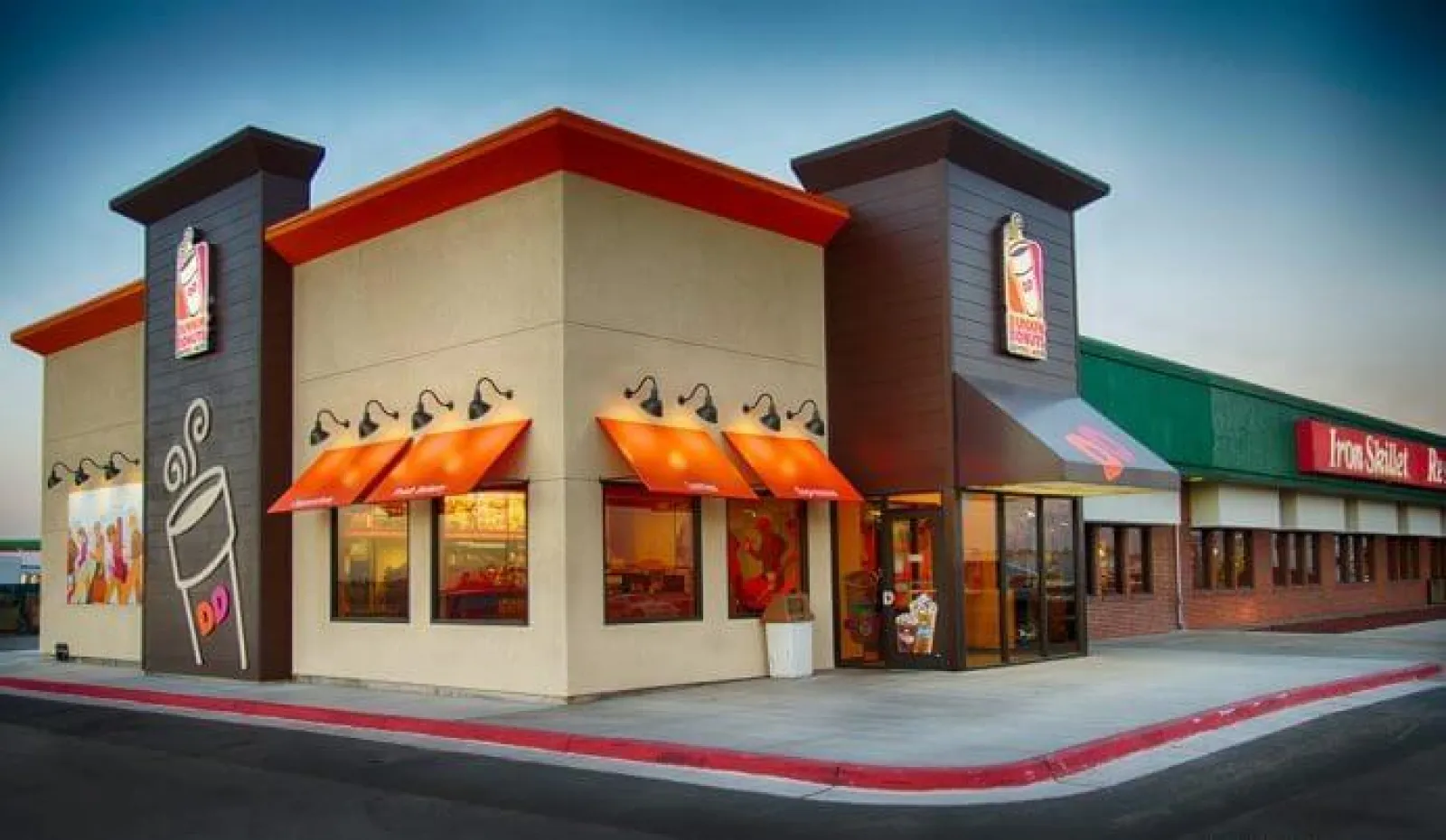 Dunkin' Donuts storefront with orange awnings and coffee cup logo on a clear day