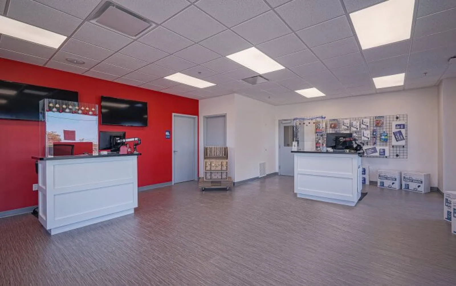 Spacious, modern service area with two white counters, red accent wall, and product displays under fluorescent lighting