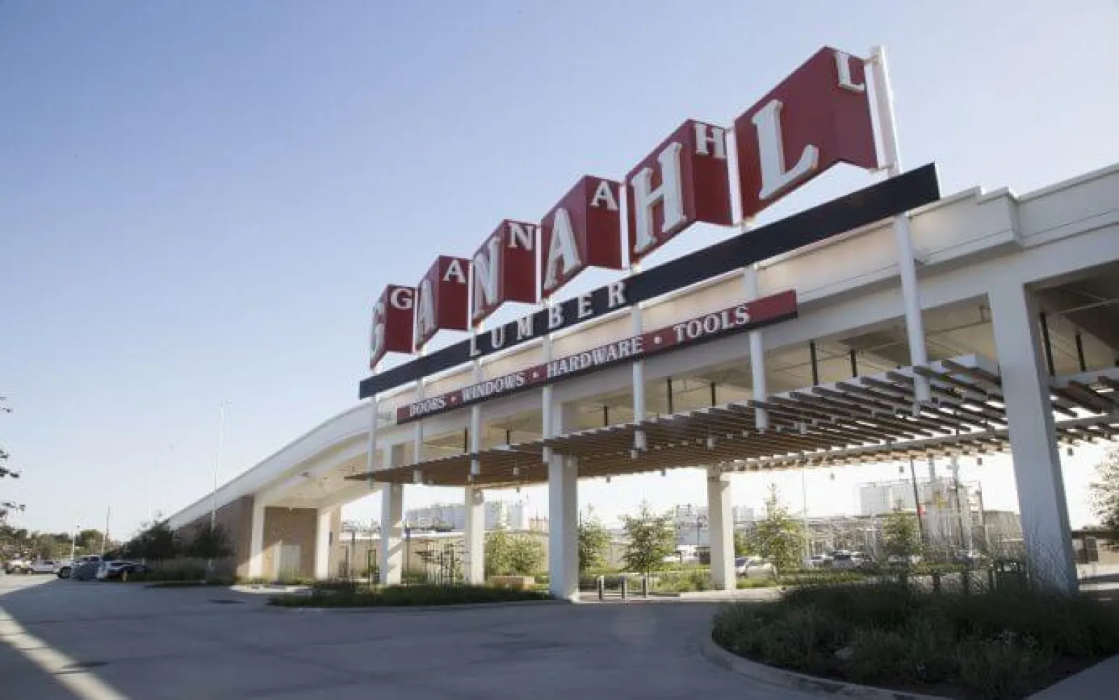 Large Canadian HL Lumber store sign above an entrance with clear sky and parking area.