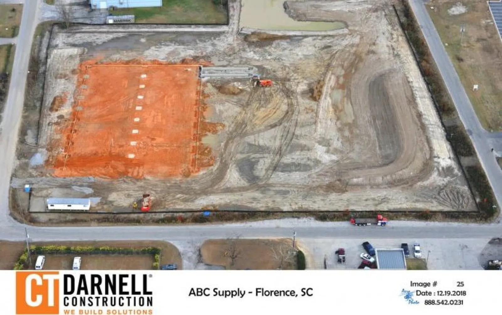 Aerial view of construction site with excavated red soil area and heavy machinery by CT Darnell Construction